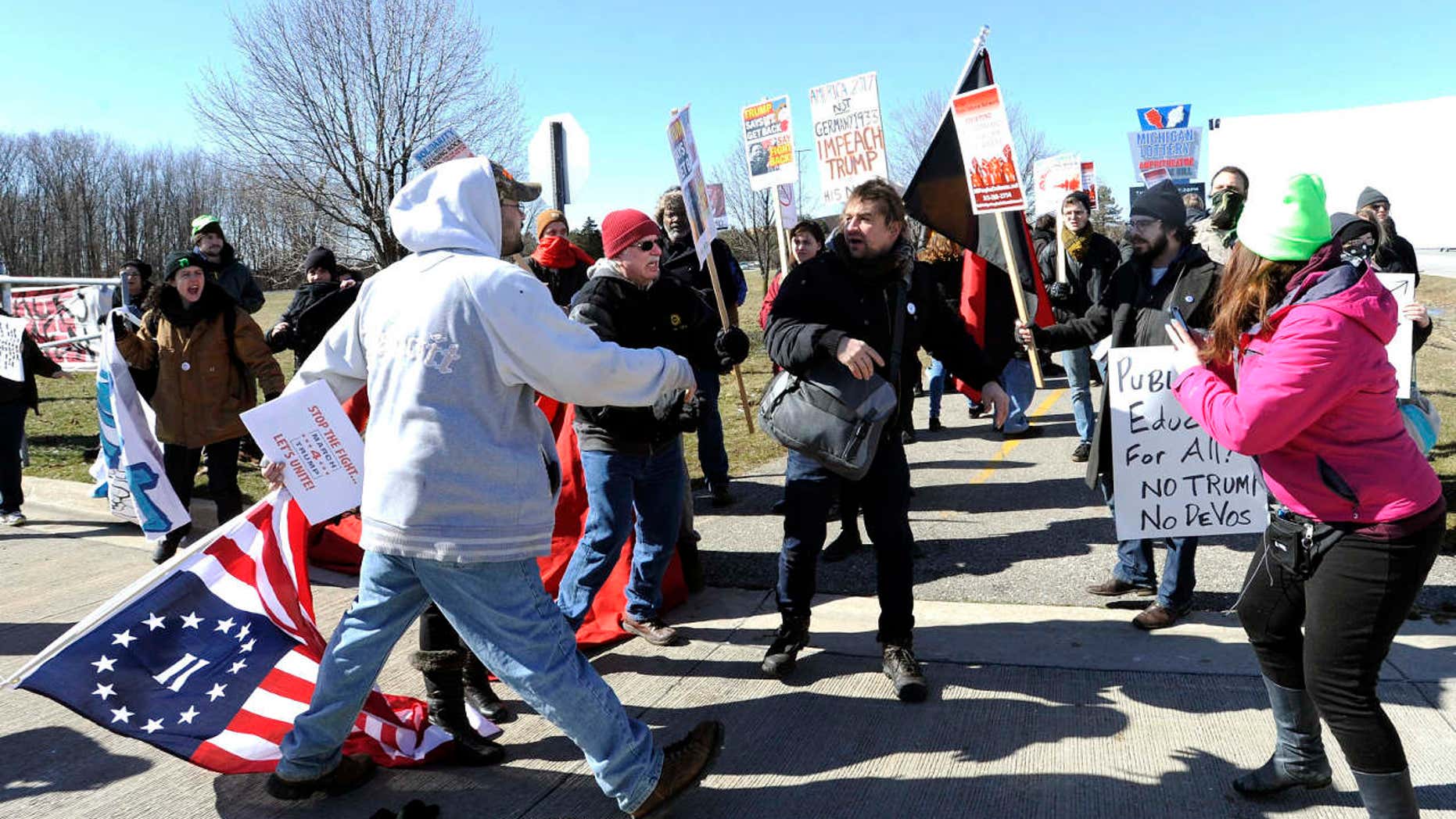 March 4, 2017: Trump supporters, left, and protestors, right, briefly push and shove each other after a woman was allegedly hit and a sign thrown on the ground during a rally in support of President Donald Trump at Freedom Hill County Park in Sterling Heights, Mich.