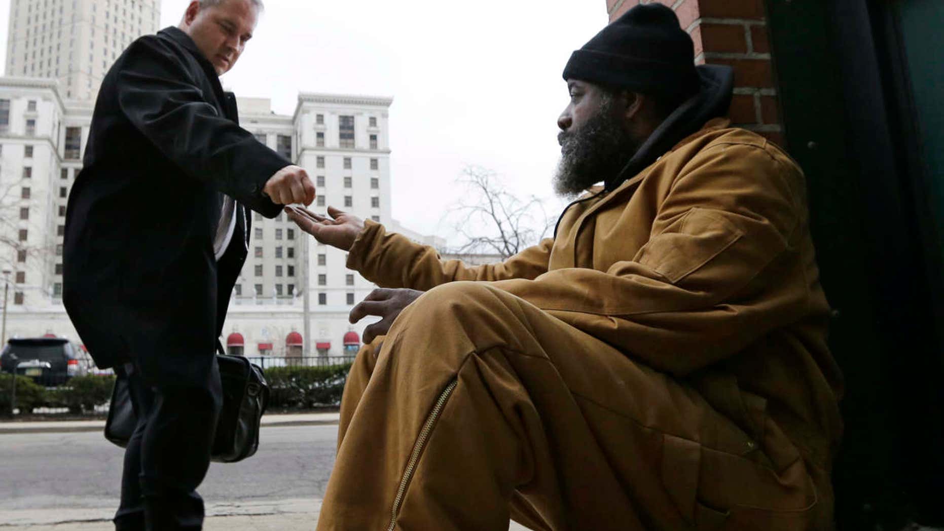 Kenny Chapman, right, 53, receives coins from a man, Tuesday, Feb. 28, 2017, in downtown Cleveland.