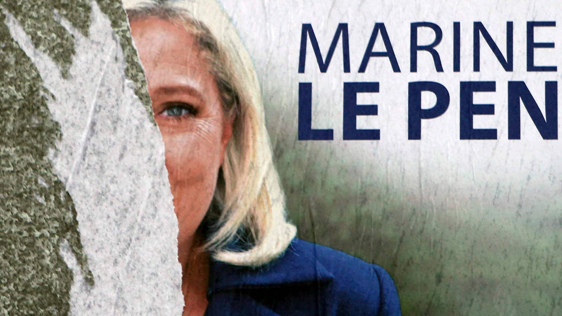 FILE - In this Dec. 11, 2015 file photo, a defaced poster of French far-right party leader Marine Le Pen is seen in Henin-Beaumont, northern France.