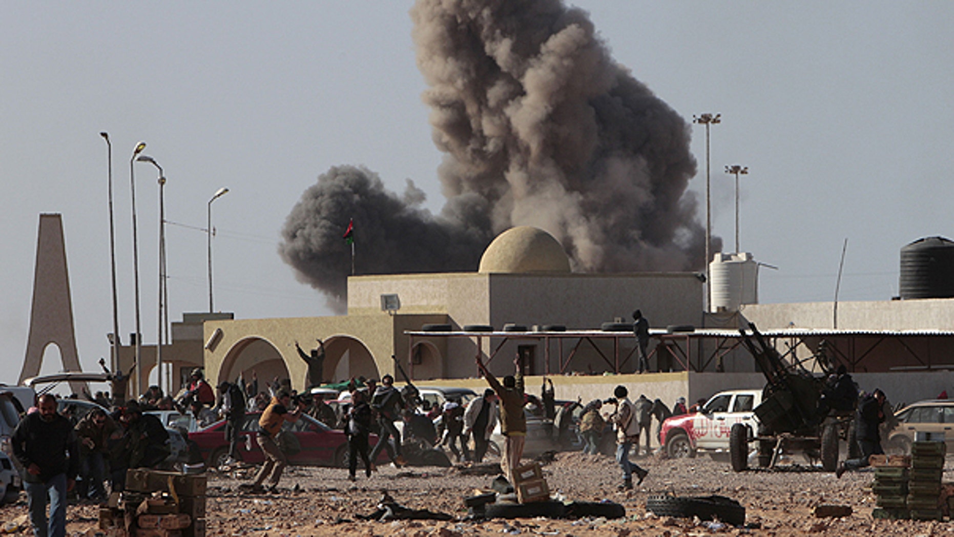 March 7: Anti-Qaddafirebels run away as smoke rises following an air strike by Libyan warplanes near a checkpoint in the oil town of Ras Lanouf, eastern Libya.