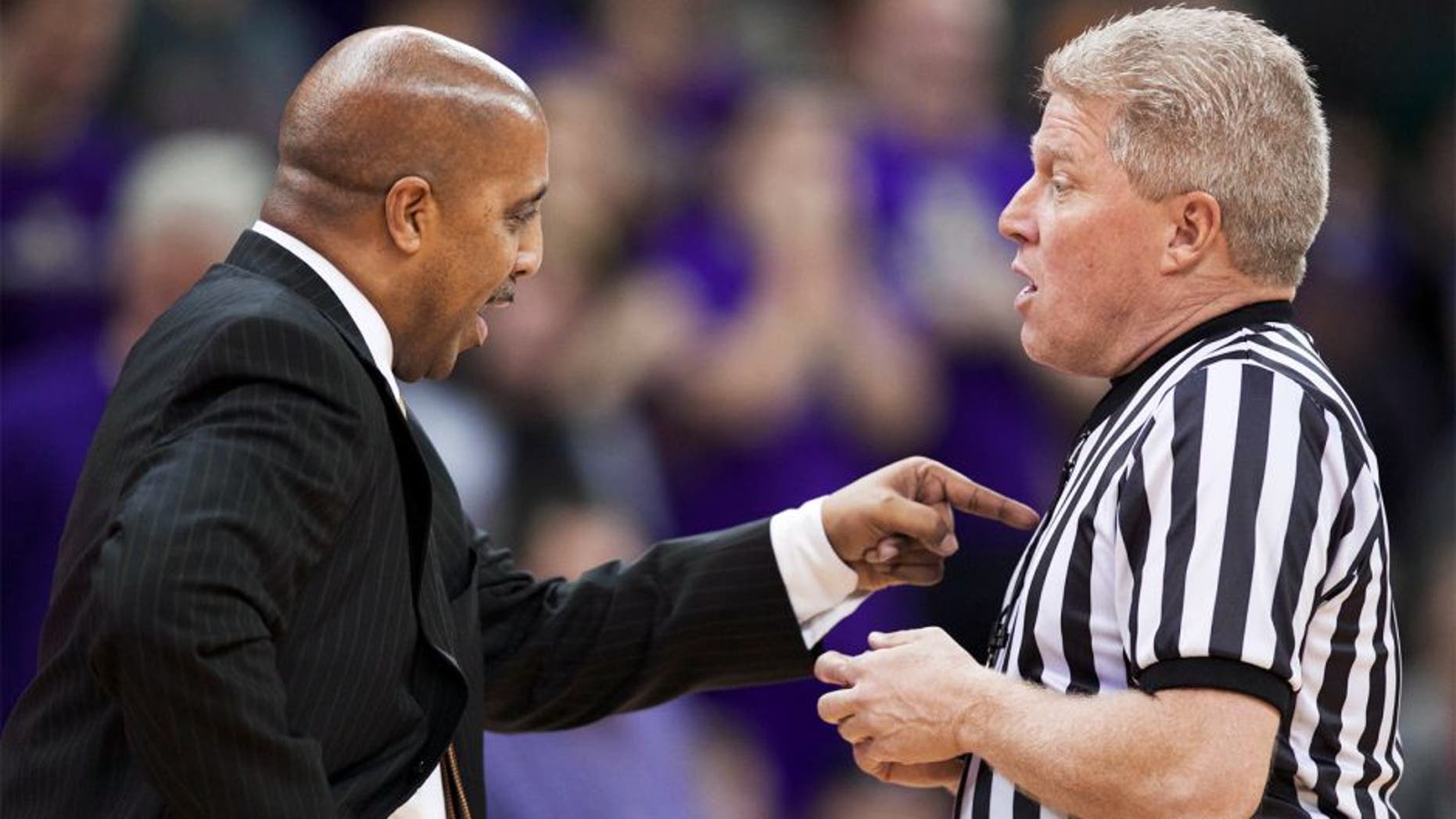 Washington head coach Lorenzo Romar, left, disputes a call with an official in the second half of an NCAA college basketball game against UCLA, Thursday March 6, 2014, in Seattle. UCLA won 91-82. (AP Photo/Stephen Brashear)