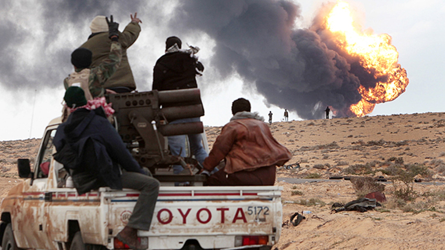 March 9: Anti-Qaddafi rebels ride on a truck with a multiple rocket launcher, as flames rises from a fuel storage facility that was attacked during fighting with pro-fighters, in Sedra, eastern Libya.
