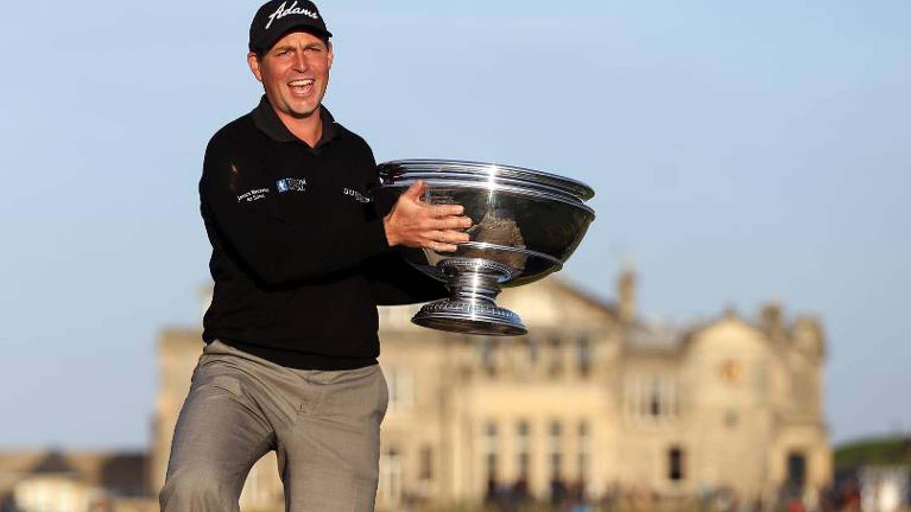 English golfer David Howell poses on the Swilcan Bridge with the trophy after winning the The Alfred Dunhill Links Championships golf competition on The Old Course at St Andrews, Fife, Scotland on September 29, 2013.
