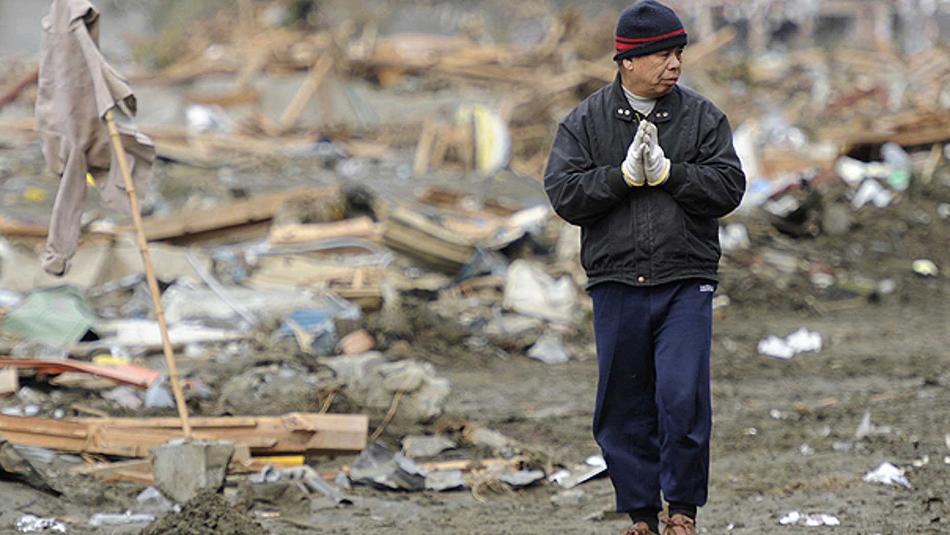 March 15: A man prays his family members at tsunami-devastated area in Rikuzentakata, Iwate prefecture, Japan.