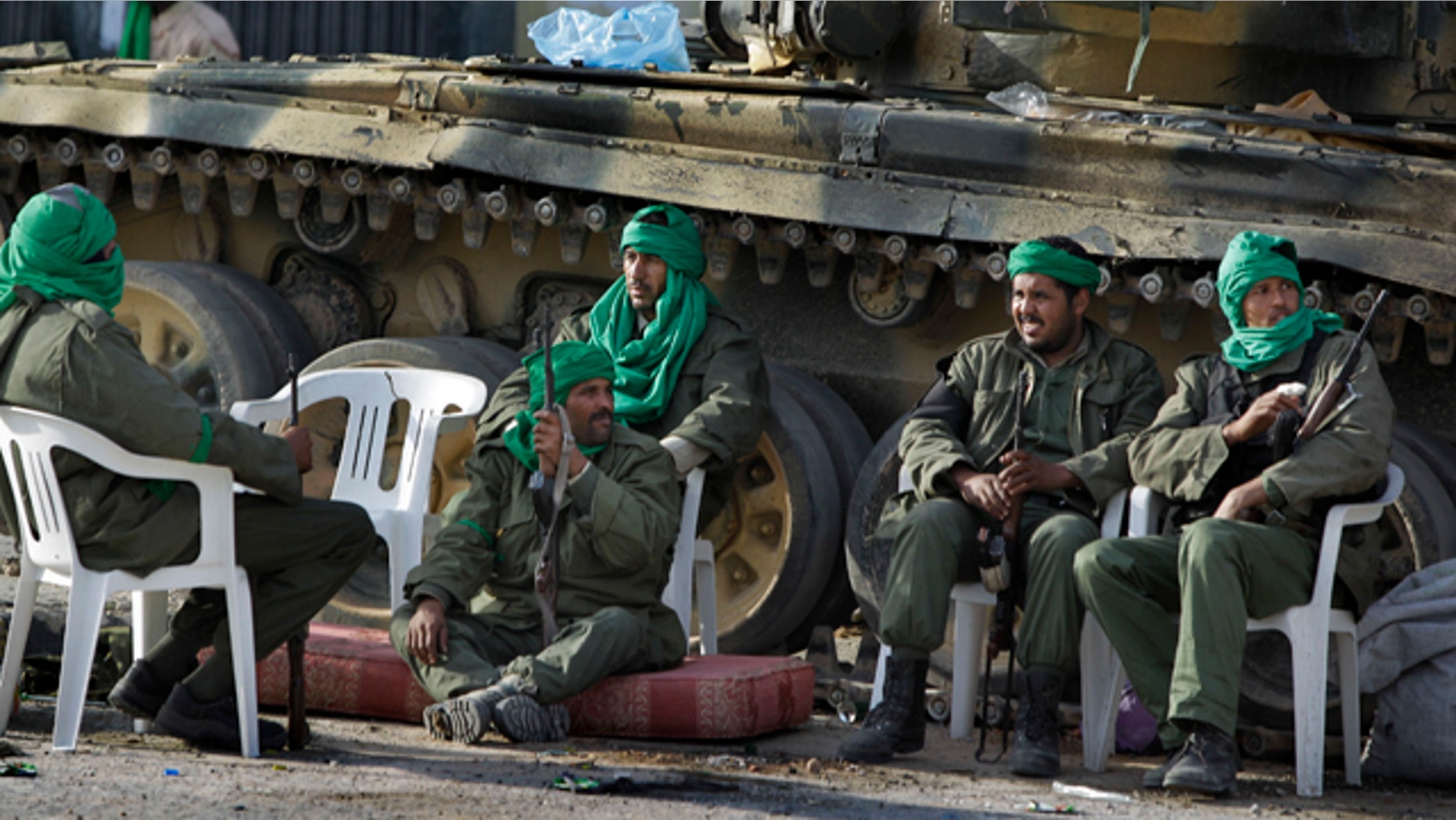 March 11: In this photo taken during a government organized visit for foreign media, pro-Qaddafi soldiers sit by their tank next to a destroyed building in the main square of Zawiya.