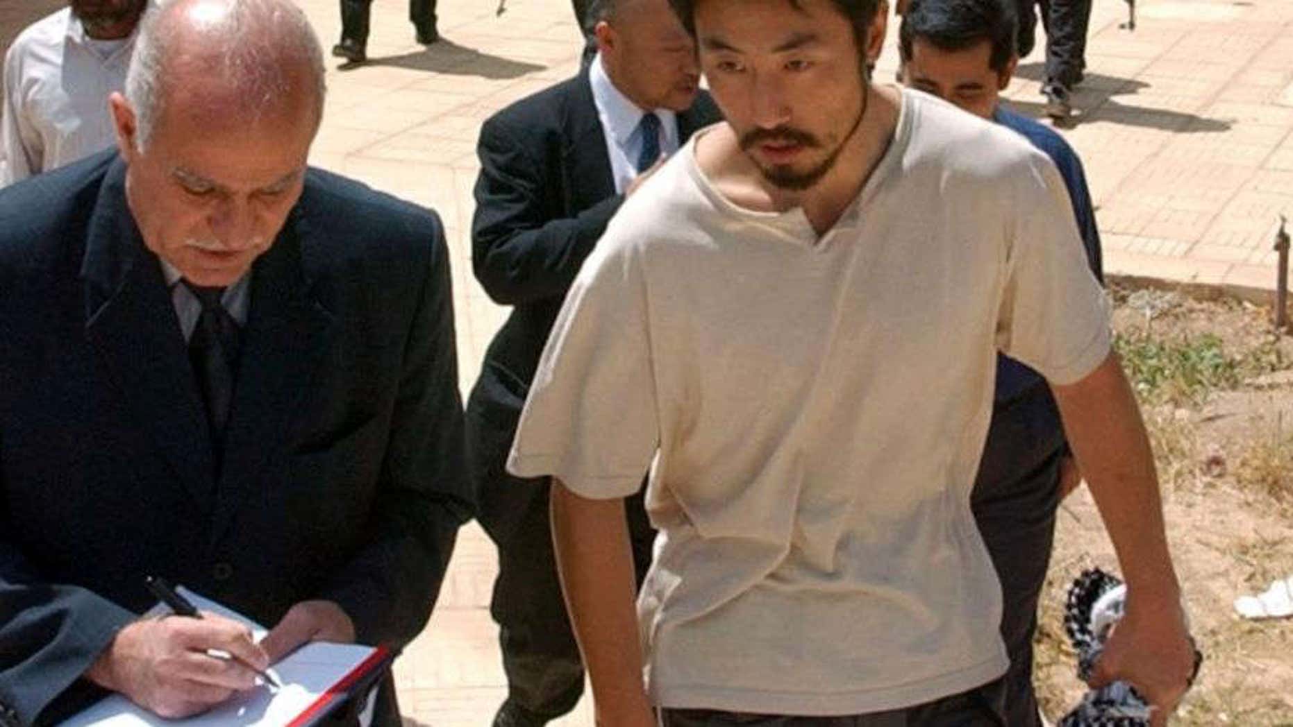 FILE - In this April 17, 2004 file photo, Japanese freelance journalist Jumpei Yasuda, right, is escorted after being released at Umm Al-Qura mosque in Baghdad, Iraq.
