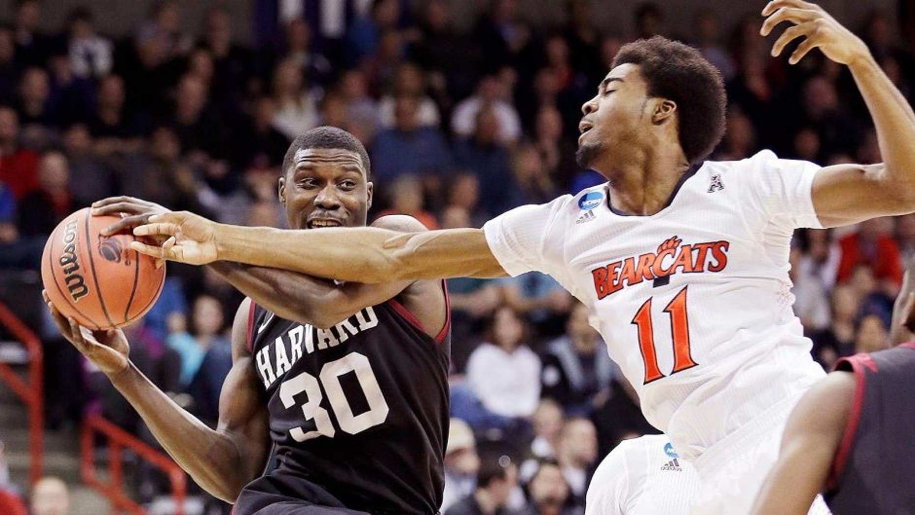 Harvard's Kyle Casey (30) tries to hold onto a rebound in front of Cincinnati's Jermaine Lawrence during the first half of a second-round game in the NCAA college basketball tournament in Spokane, Wash., Thursday, March 20, 2014. (AP Photo/Elaine Thompson)