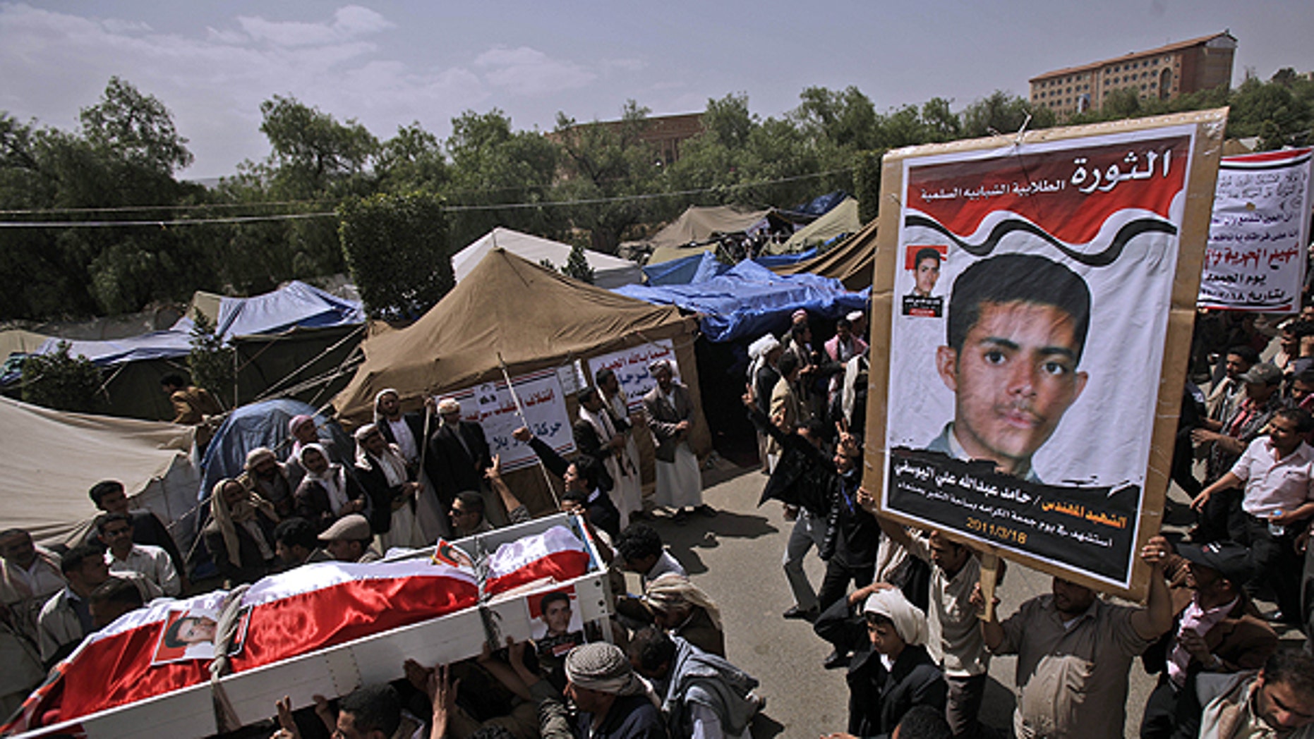 March 20: Anti-government protestors carry the body of Hamid Ali, his poster seen right, who was killed on Friday's clashes with Yemeni security forces, during his funeral procession in Sanaa.