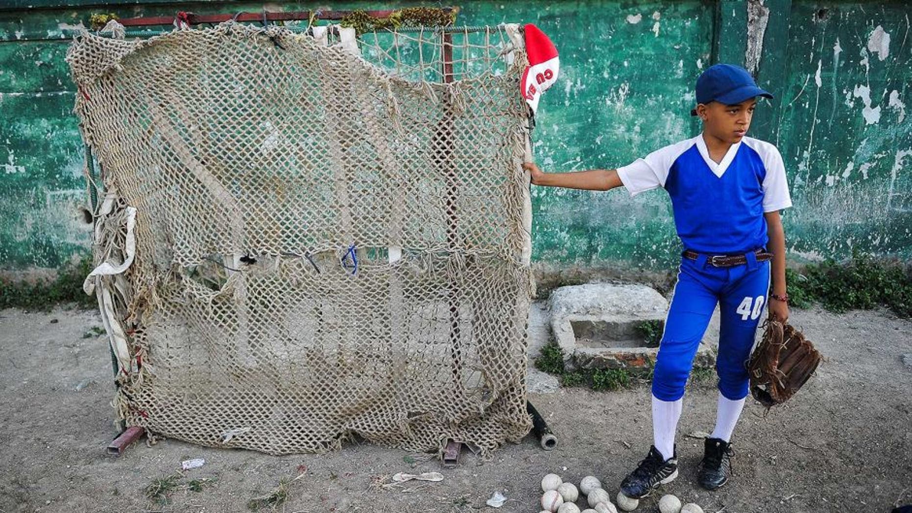 A Cuban child looks at a baseball practice in Havana, on March 16, 2016. Cubans look forward to the baseball game between the US Tampa Bay Rays team and the Cuban team, which will take place on March 22, with the presence of US President Barack Obama. AFP PHOTO/ YAMIL LAGE / AFP / YAMIL LAGE (Photo credit should read YAMIL LAGE/AFP/Getty Images)