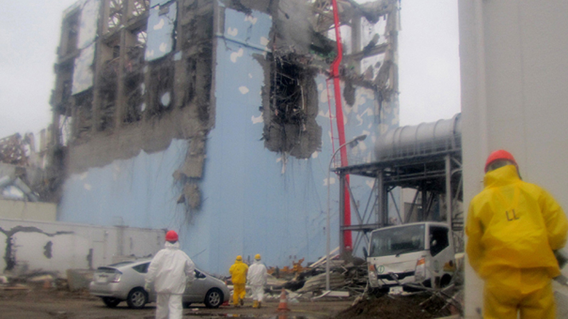 March 22: In this photo released by Tokyo Electric Power Co. (TEPCO) , workers in protective suits conduct cooling operation by spraying water at the damaged No. 4 unit of the Fukushima Dai-ichi nuclear complex in Okumamachi, northeastern Japan.