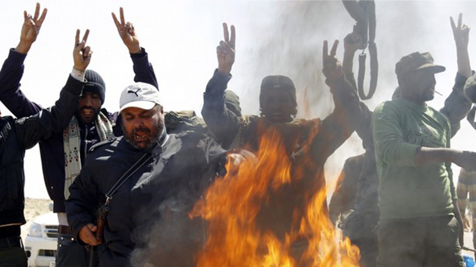 March 25: Rebel fighters shout over a fire ignited to burn clothes of soldiers loyal to Libyan leader Muammar al-Qaddafi along a Benghazi-Ajdabiyah road near Ajdabiyah.
