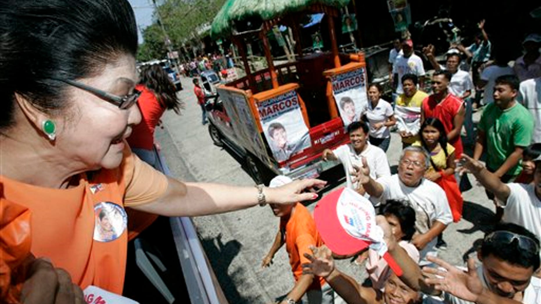 March 26: Imelda Marcos, left, widow of the late strongman Ferdinand Marcos, gives away caps during a campaign sortie in Batac, Ilocos Norte, northern Philippines. Marcos is running for a seat in the house of representatives along with her son, senatorial bet Ferdinand "Bongbong" Marcos Jr., and her daughter, Imee, a gubernatorial candidate in the Marcos's political stronghold.