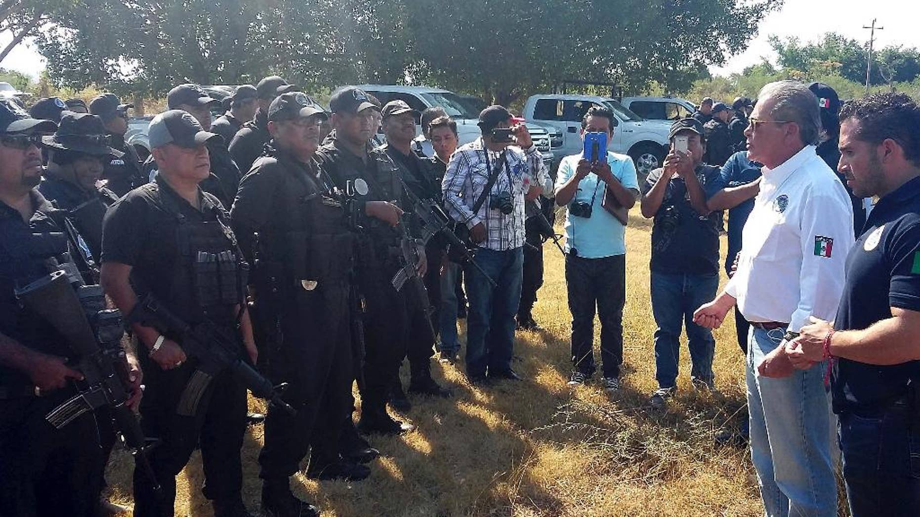 In this photo released by Guerrero state Attorney Generals Office, Javier Olea, attorney general of Guerrero state, right, talks to police at the start of a security operation in San Jeronimo El Grande, Mexico, Thursday, Nov. 24, 2016. Soldiers and police fanned out Friday across Guerrero state, chasing a wounded gang leader and trying to quell a wave of violence that included the discovery of hidden graves holding dozens of bodies and a camp where gunmen stored the severed heads of nine rivals in a cooler. (Guerrero state Attorney Generals Office via AP)