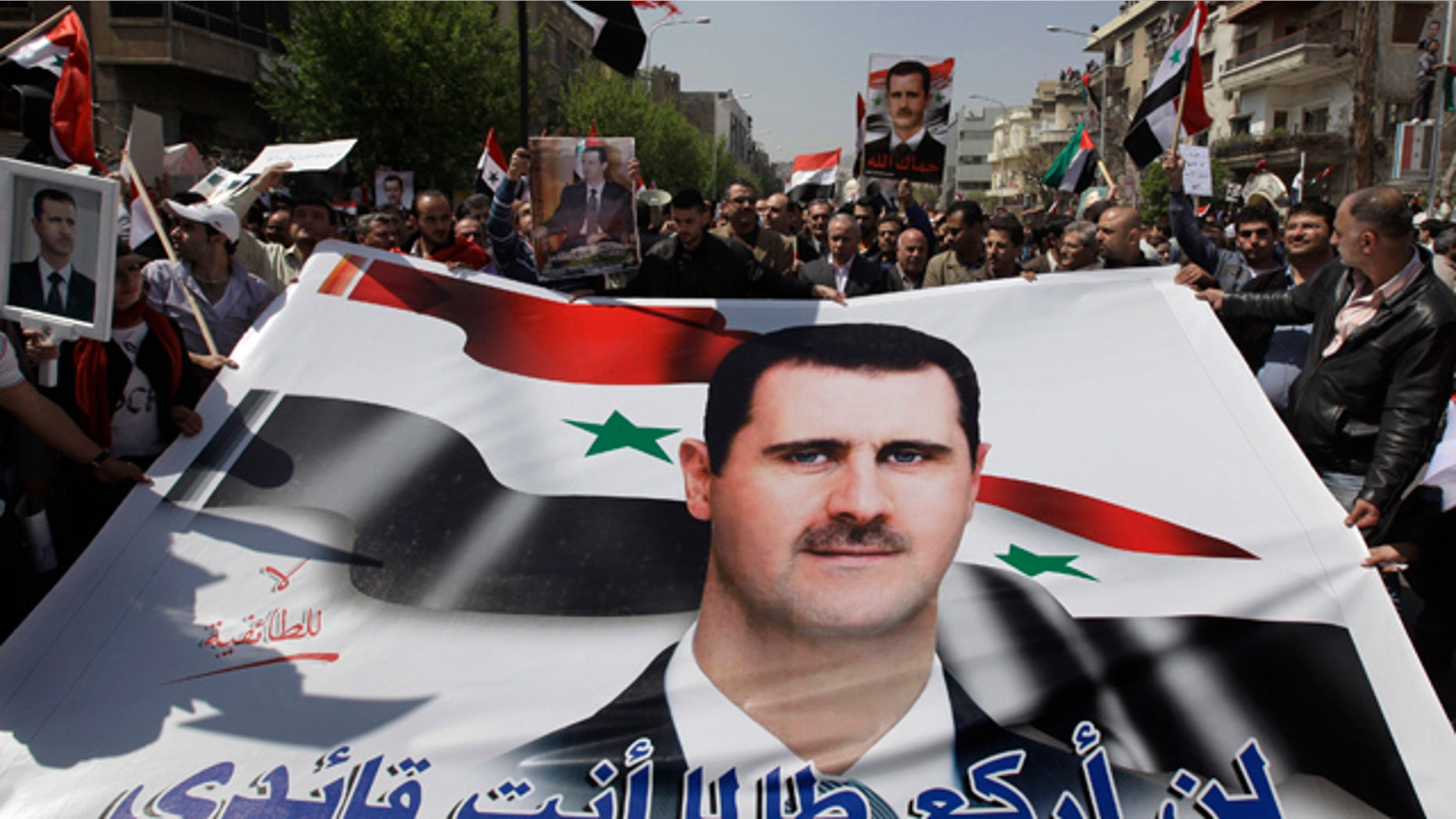 March 29: Pro-Syrian President Bashar Assad supporters hold Assad's poster with Arabic words reading: "I'll not kneel as long as you are my leader" as they demonstrate to show their support for their president, in Damascus, Syria.