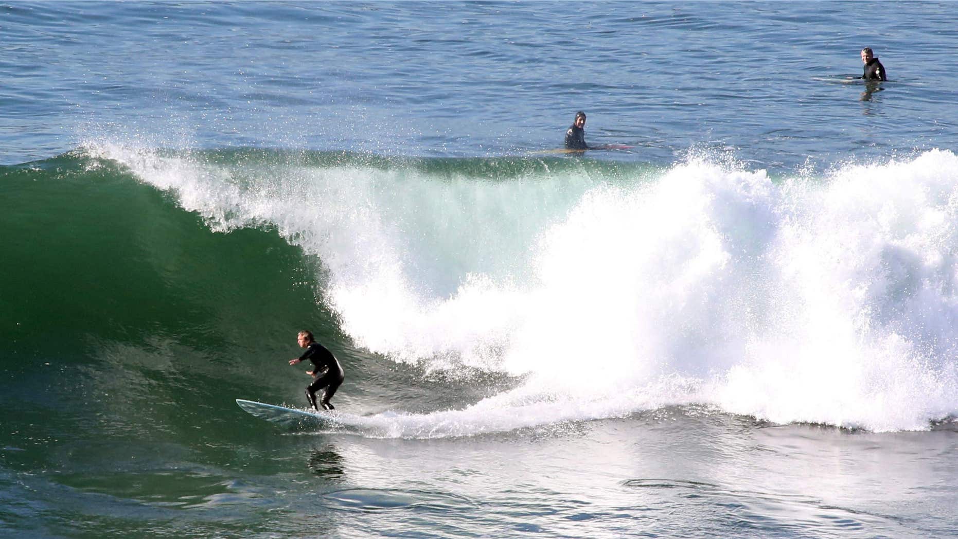 FILE - In this Tuesday, Dec. 8, 2015, file photo, surfers ride a wave at Lunada Bay in Palos Verdes Estates, Calif.