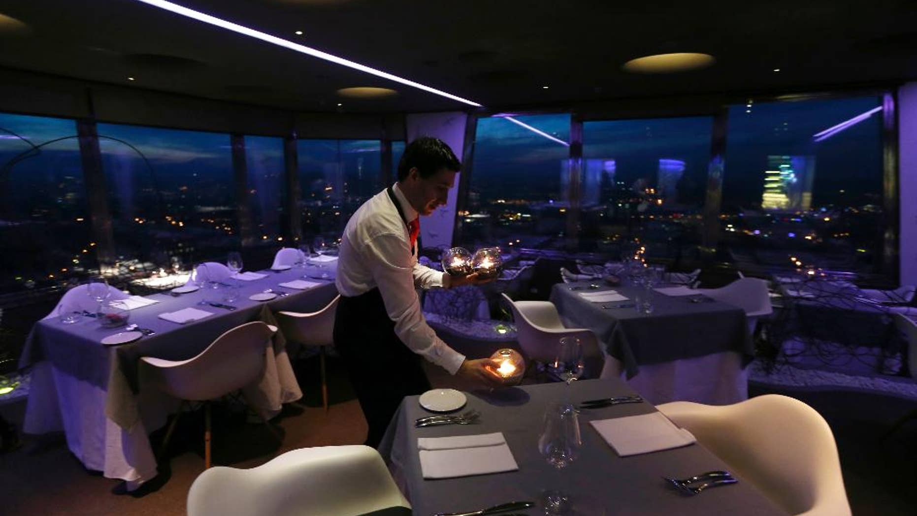 FILE- In this March 6, 2013 file photo, a waiter sets a candle on a table in a restaurant at the Zizkov television tower in Prague, Czech Republic. The Czech Republic has launched a new system to increase tax revenue by requiring bars and restaurants to report their sales online. (AP Photo/Petr David Josek)
