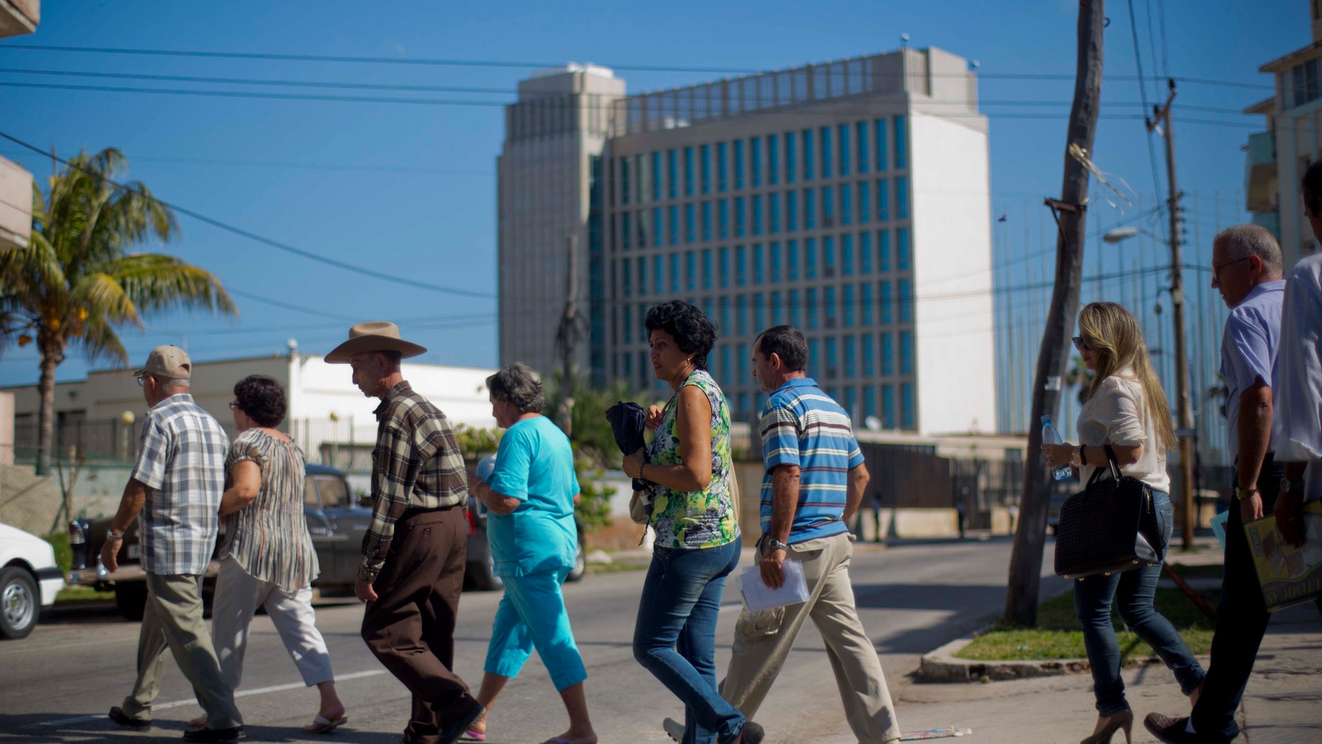 In this photo taken Jan. 13, 2014, people walk in line while entering the U.S. Interests Section to apply for U.S. travel visas in Havana, Cuba. Cubans are taking advantage of a travel reform that went into effect a year ago, when the government scrapped an exit visa requirement that for five decades had made it difficult for most islanders to go abroad. Now they are traveling in record numbers. (AP Photo/Ramon Espinosa)