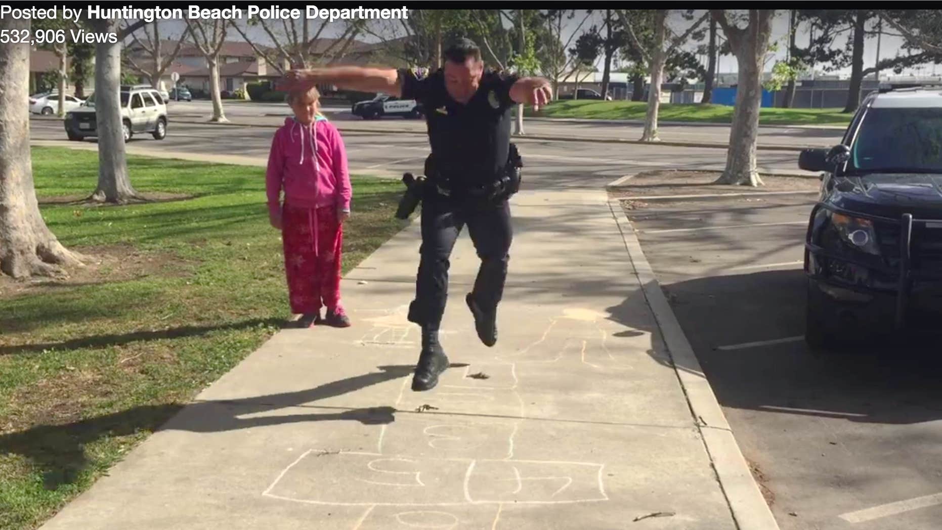 In this Wednesday, March 30, 2016 still frame from video provided by the Huntington Beach, Calif., Police Department, Officer Zach Pricer shows an 11-year-old homeless girl how to hopscotch on a street in Huntington Beach, Calif.