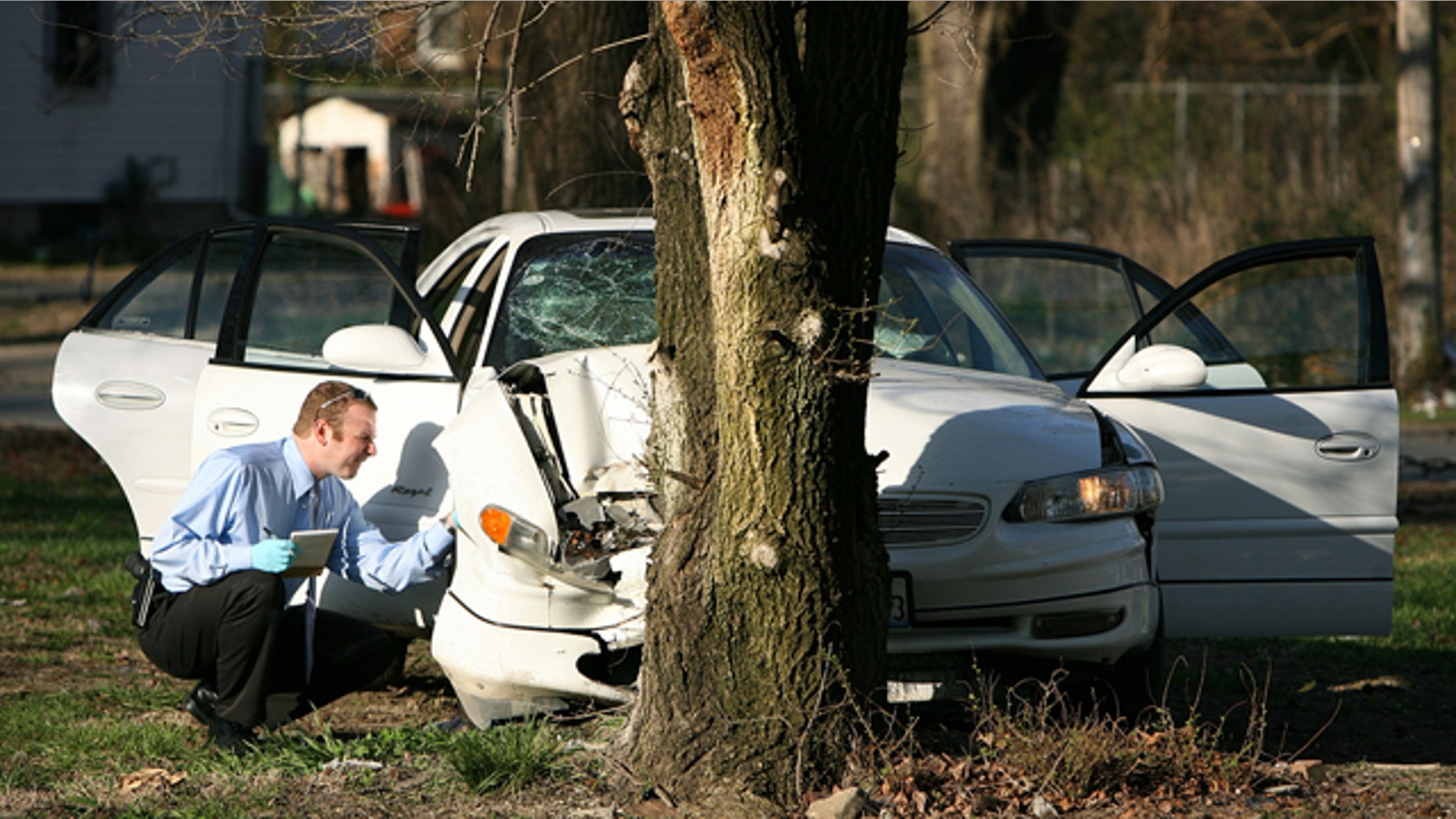 April 1: A crime scene investigator combs the wreckage of Washington Park Mayor John Thornton's car.