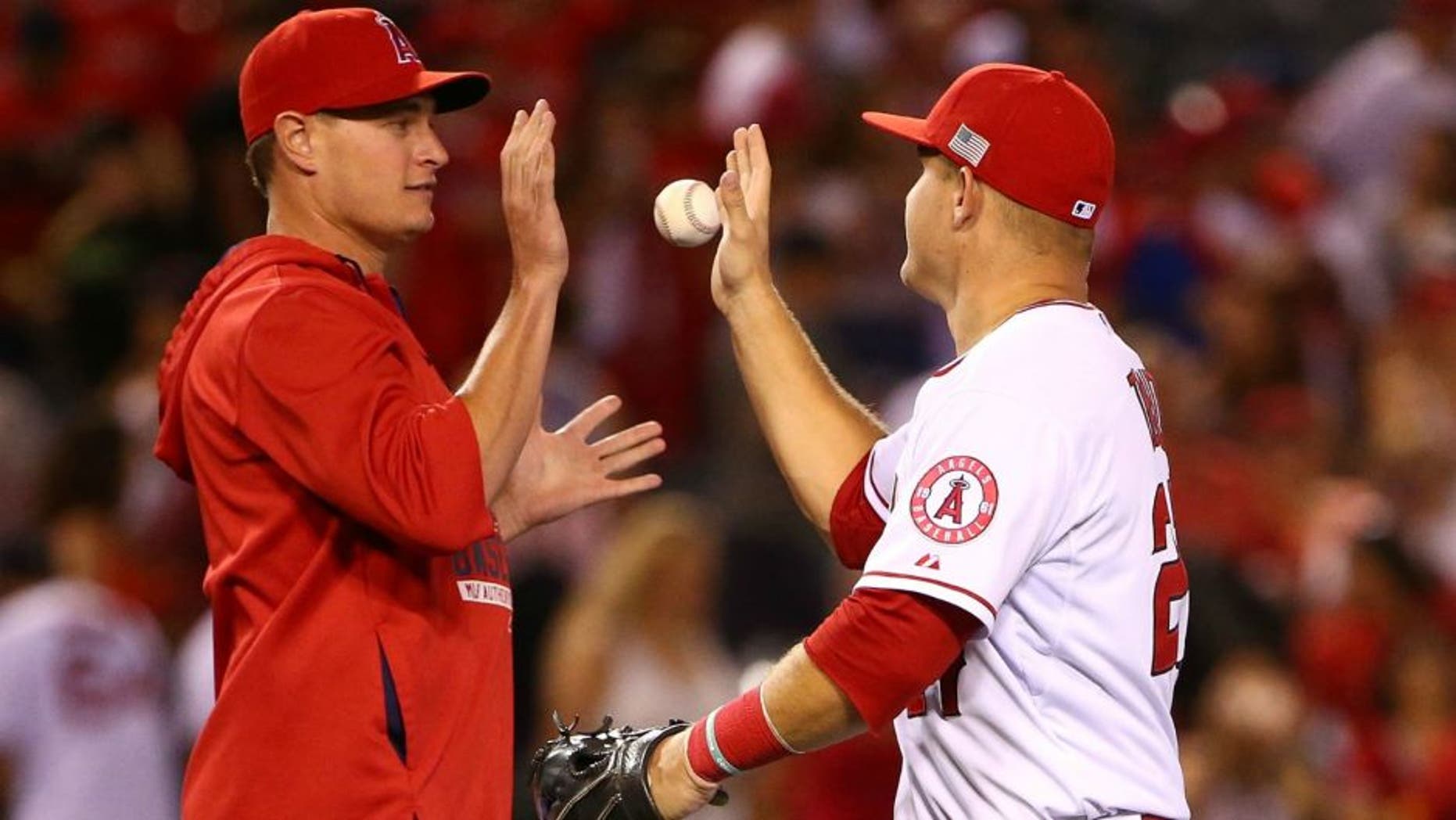 Mike Trout #27 of the Los Angeles Angels of Anaheim tosses a ball to teammate Garrett Richards #43 as they celebrate after their MLB game against the Houston Astros at Angel Stadium of Anaheim on September 11, 2015 in Anaheim, California. The Angels defeated the Astros 3-2. (Photo by Victor Decolongon/Getty Images)