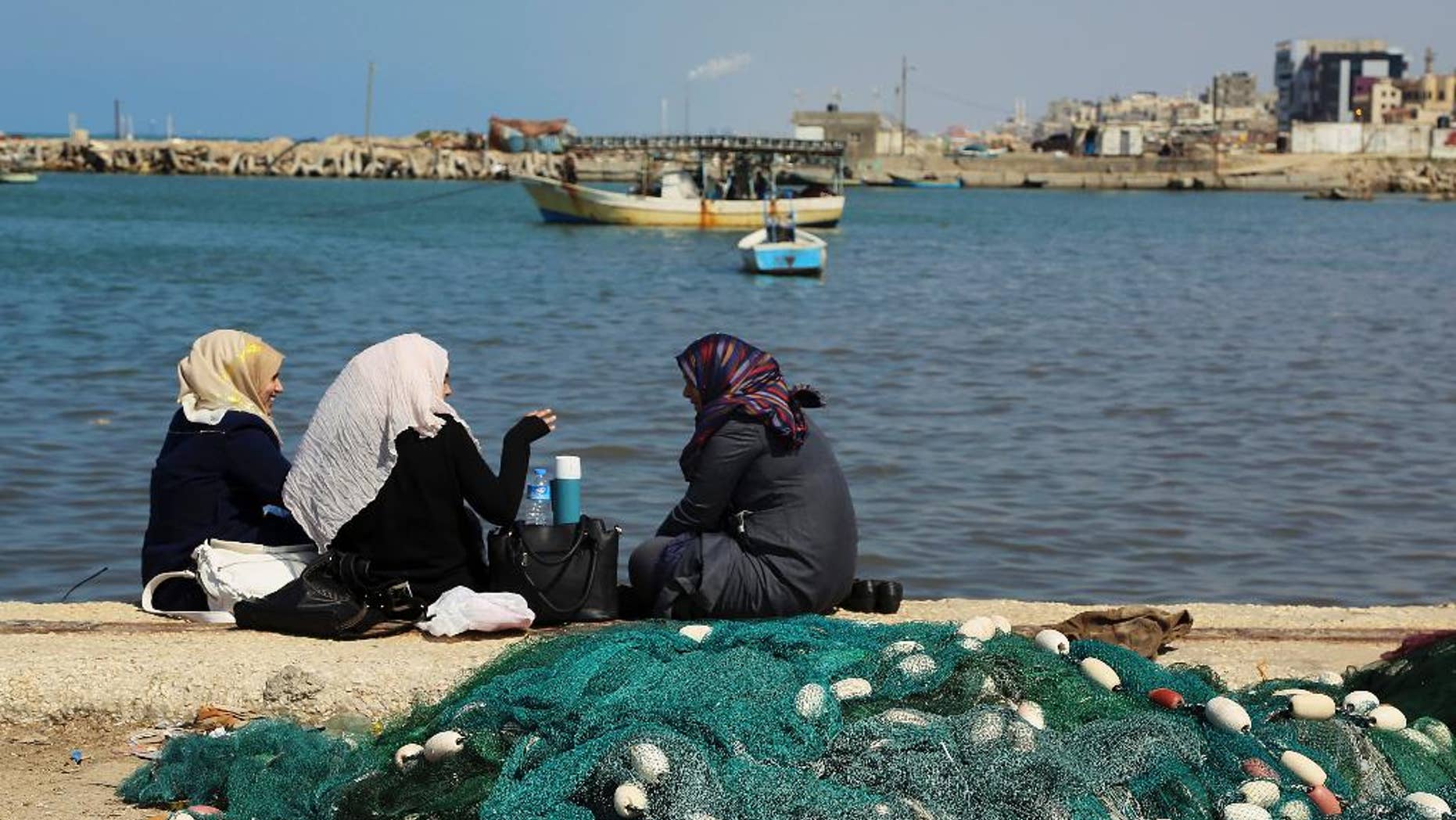 Palestinian women chat while enjoying the sunny weather at the fishermen's port in Gaza City in the northern Gaza Strip on Thursday, March 5, 2015. (AP Photo/Adel Hana)