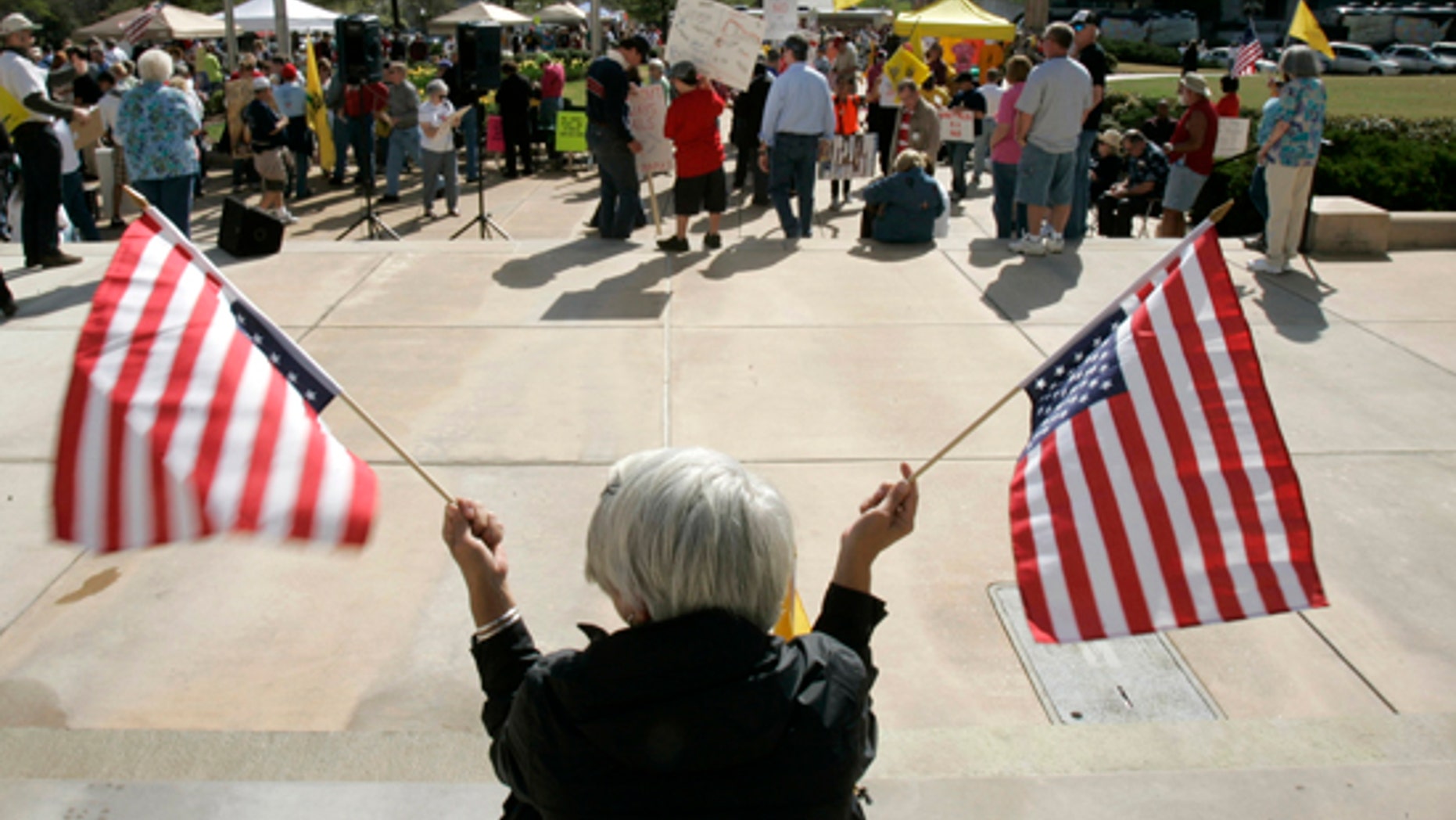 An unidentified woman holds upside-down flags before a Tea Party Express rally at the Arkansas state Capitol in Little Rock, Ark., Saturday, April 3, 2010.(AP)