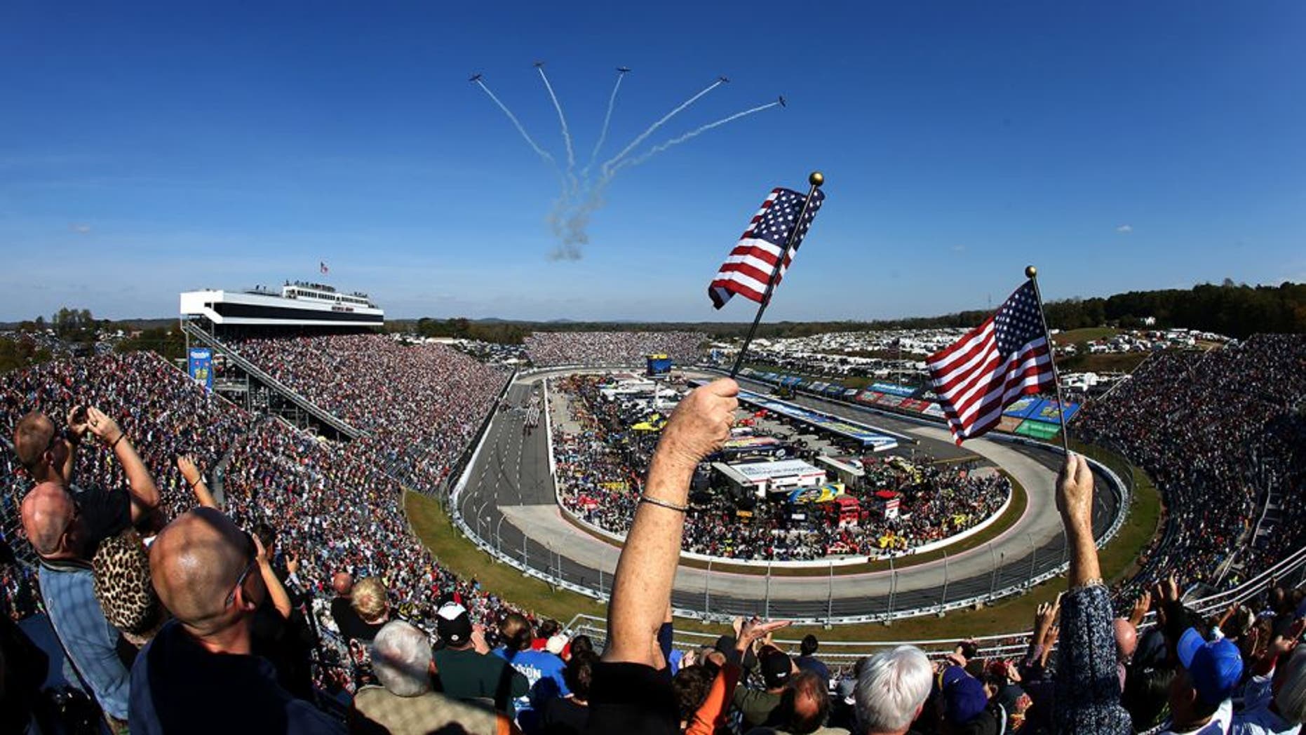 MARTINSVILLE, VA - OCTOBER 27: Fans wave American flags as five CJ-6A's from Affordable Warbirds perform a flyover prior to the NASCAR Sprint Cup Series Goody's Headache Relief Shot 500 Powered By Kroger at Martinsville Speedway on October 27, 2013 in Martinsville, Virginia. (Photo by Streeter Lecka/Getty Images)