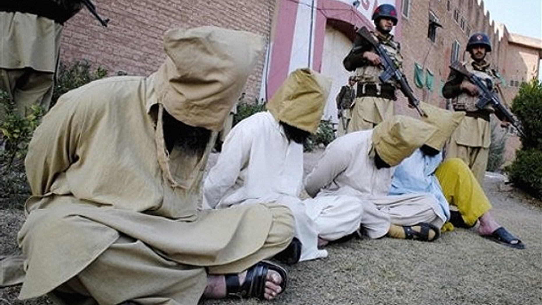 In this Dec. 19, 2010 file photo, Pakistani paramilitary soldiers stand guard next to hooded suspect militants captured during an operation in the Akakheil area, to show them to media in Bara, the main town of Pakistan's troubled tribal region Khyber along the Afghan border.