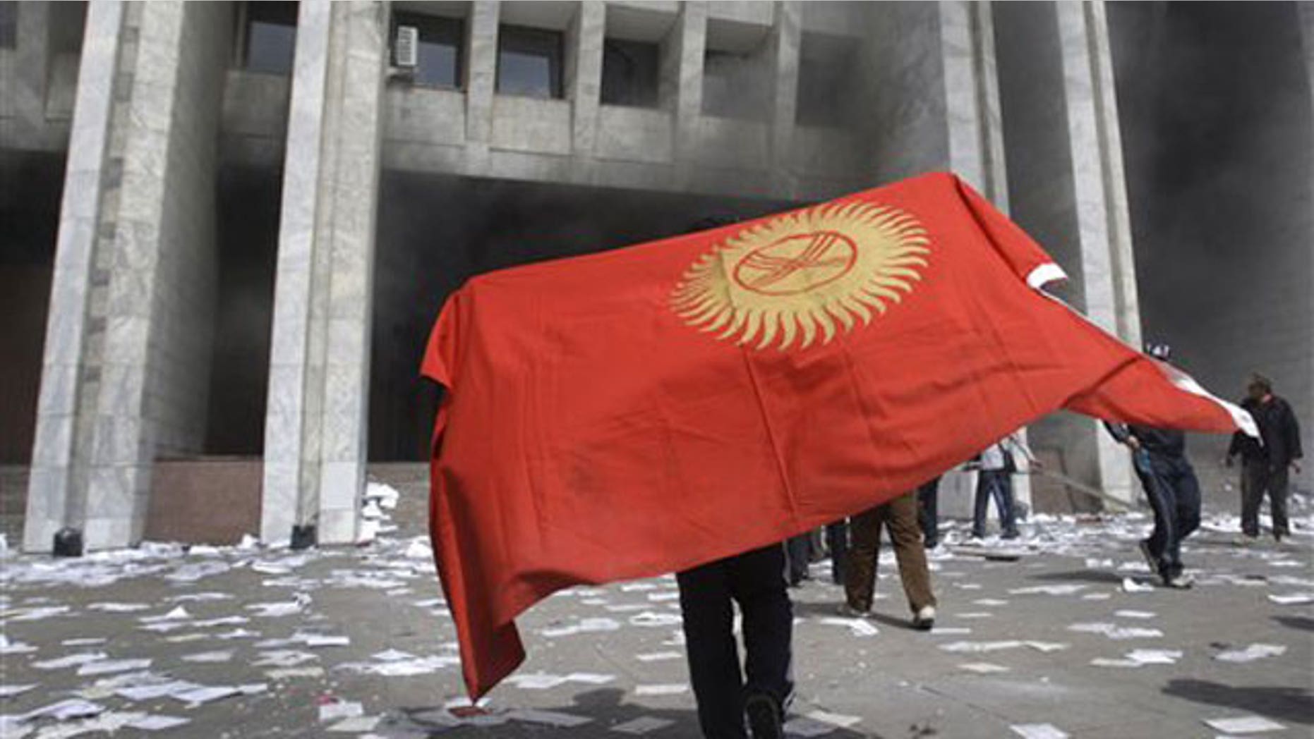 April 8: A protester covered by Kyrgyz national flag walks in front of Kyrgyz government headquarters on the central square in Bishkek.