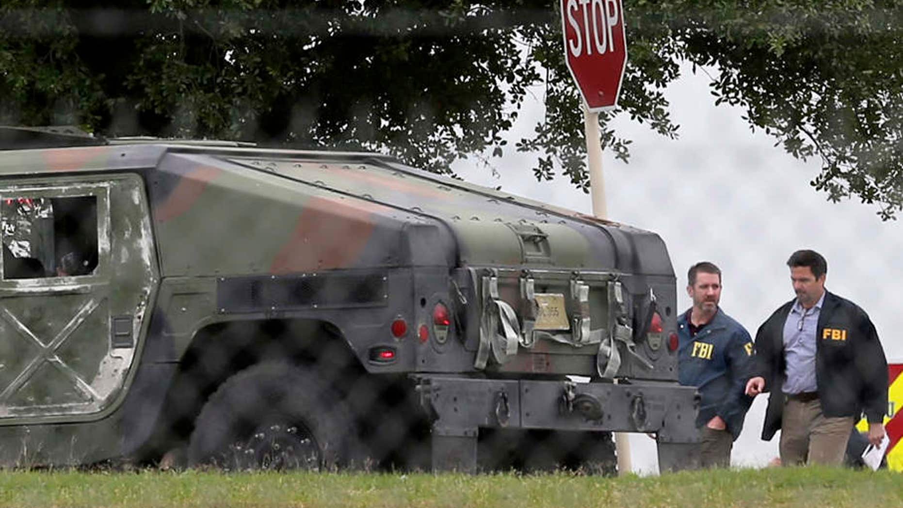 FBI officials walk behind an military vehicle near the scene of a shooting at Joint Base San Antonio-Lackland, Friday, April 8, 2016, in San Antonio