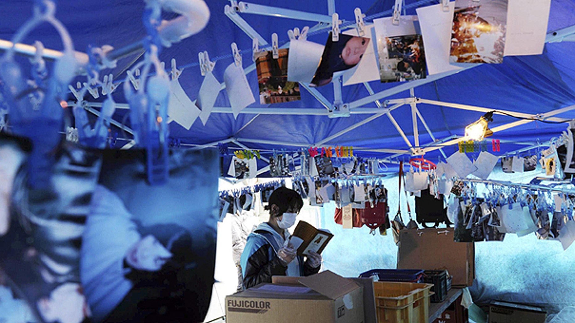 April 11: A survivor checks a personal item as photos found in the rubble hang down from ropes in Kesennuma, Miyagi Prefecture, northeastern Japan, one month to the day after an earthquake and tsunami devastated the city.