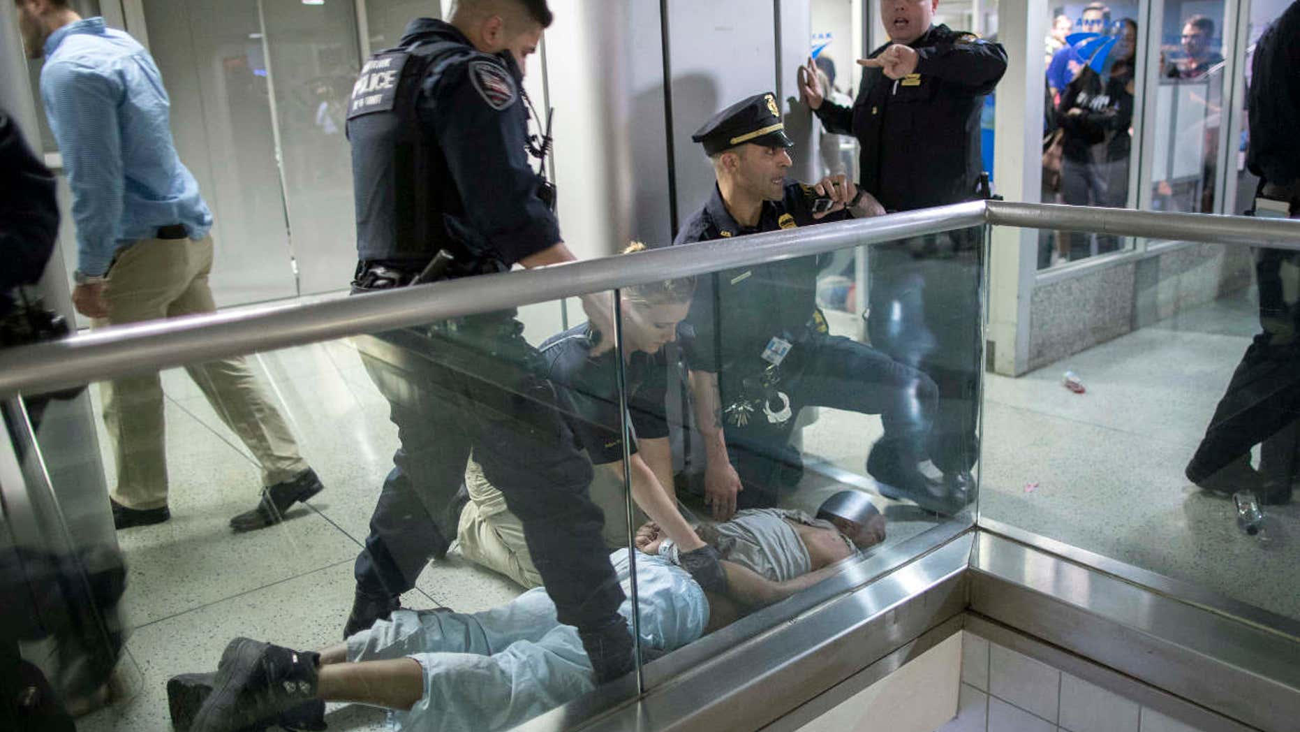 New York City police officers detain a passenger from a disabled New Jersey Transit train who became belligerent and sparked a stampede among passengers leaving the overcrowded station once the train finally arrived at New York's Penn Station, Friday, April 14, 2017.