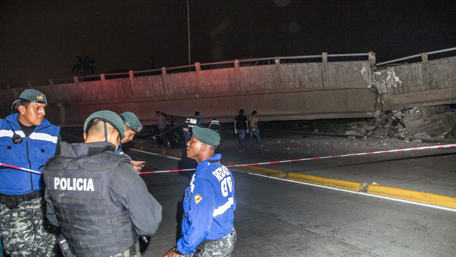 April 16, 2016: Police officers stand next to a collapsed overpass in Guayaquil, Ecuador.