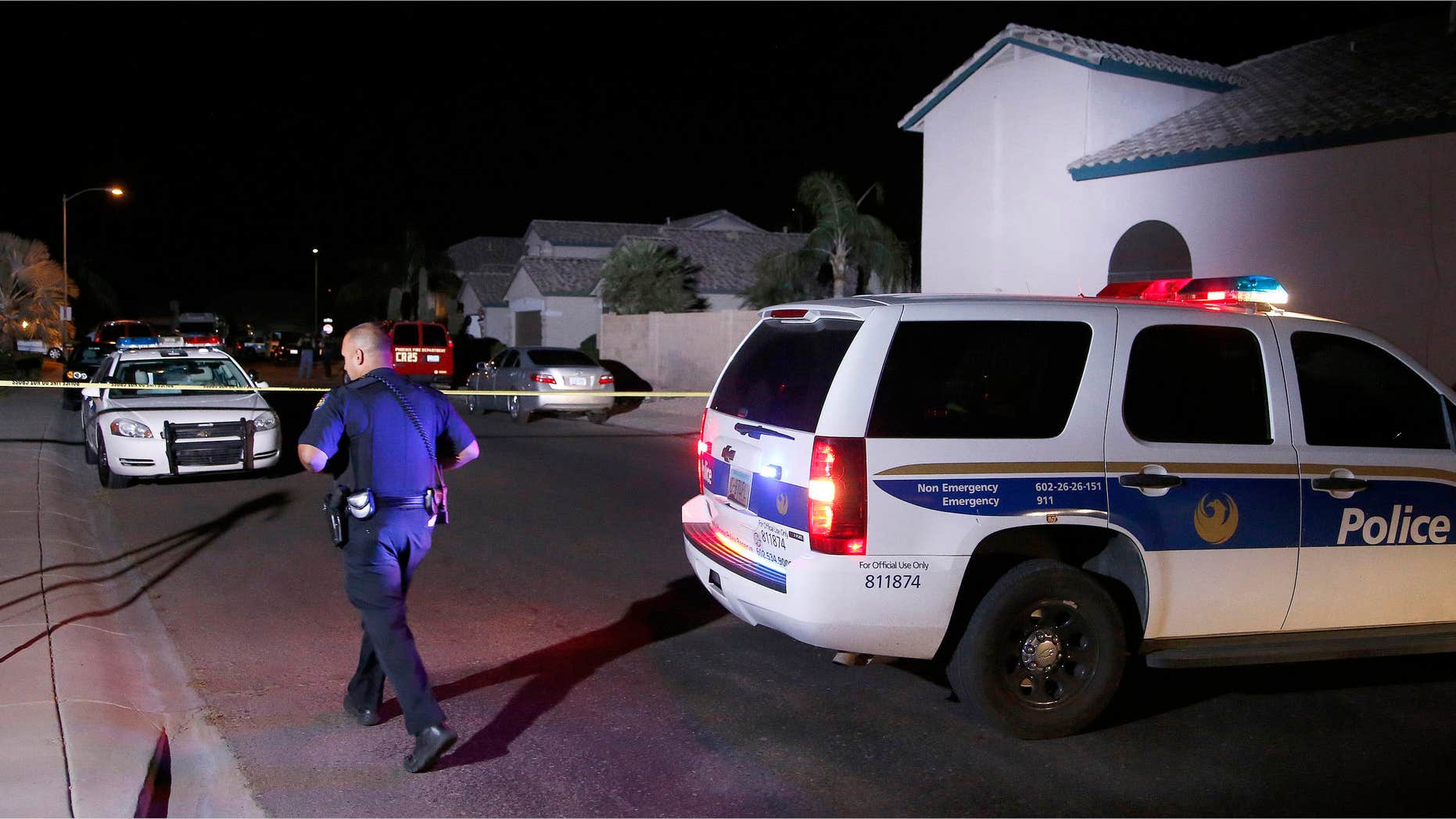 April 16, 2015: A Phoenix Police officer walks in front of the blocked off street near a home where authorities say five people were killed inside after a shooting.