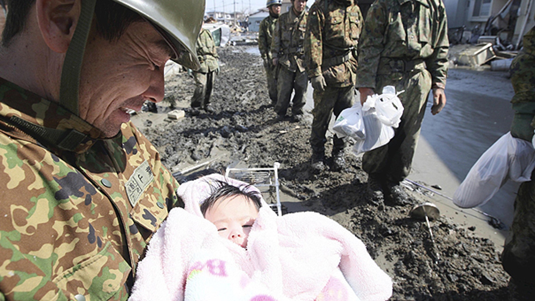 In this March 14, 2011 file photo, a Japan Self-Defense Force member reacts after rescuing a four-month-old baby girl Iroha Ishikawa in Ishinomaki, northern Japan, three days after a powerful earthquake-triggered tsunami hit the country's east coast.