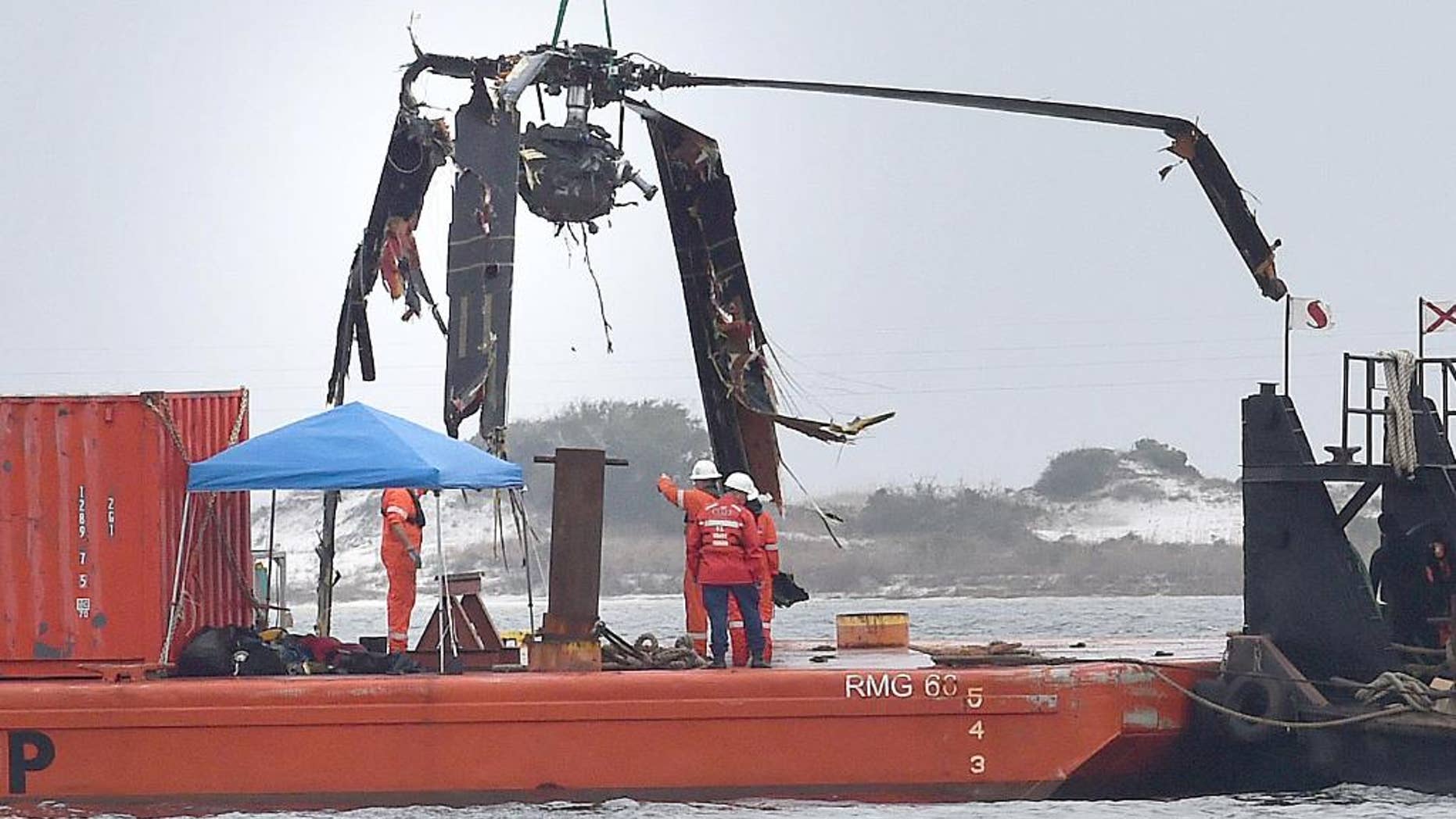 Crews lower a piece of a Black Hawk helicopter onto a barge in the Santa Rosa Sound near Pritchard Point, Friday, March 13, 2015, in Navarre, Fla. The helicopter, which crashed in dense fog during a training mission, was carrying seven Marines based in North Carolina along with four National Guard soldiers from Louisiana. All were killed. (AP Photo/Northwest Florida Daily News, Nick Tomecek)
