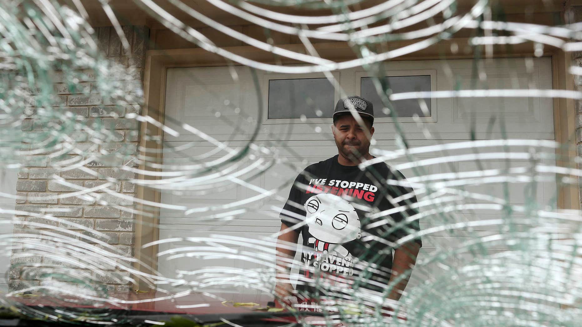 FILE - In this April 13, 2016, file photo, Rodney Rodriguez checks the damage to his 2008 Ford Escape in the Woodlake neighborhood in San Antonio, after a severe hailstorm hit the area the night before.
