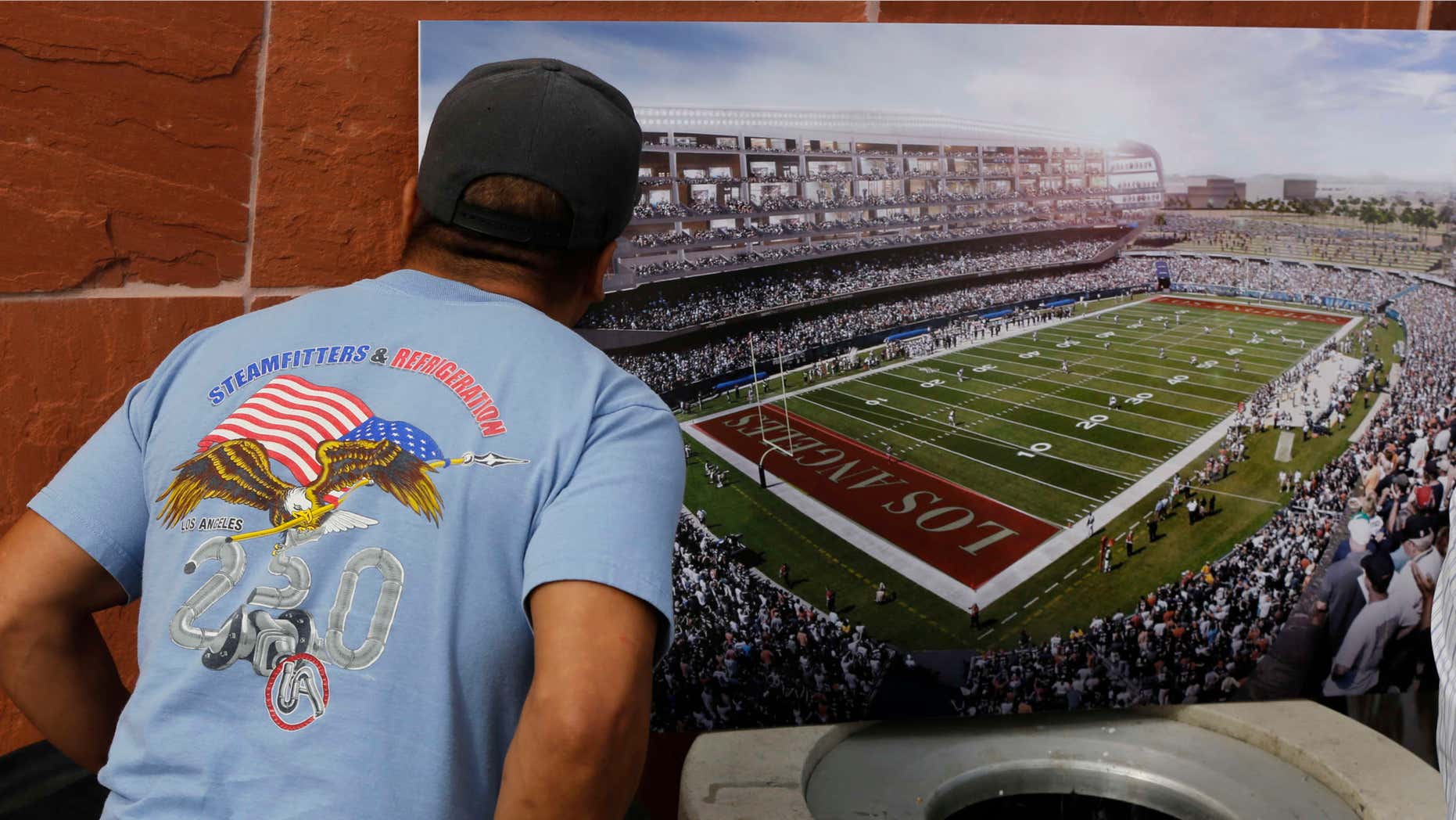 Feb. 19, 2015: A football fan checks a rendering for a proposed NFL football stadium by the owners of the San Diego Chargers and Oakland Raiders during a news conference in Carson, Calif.
