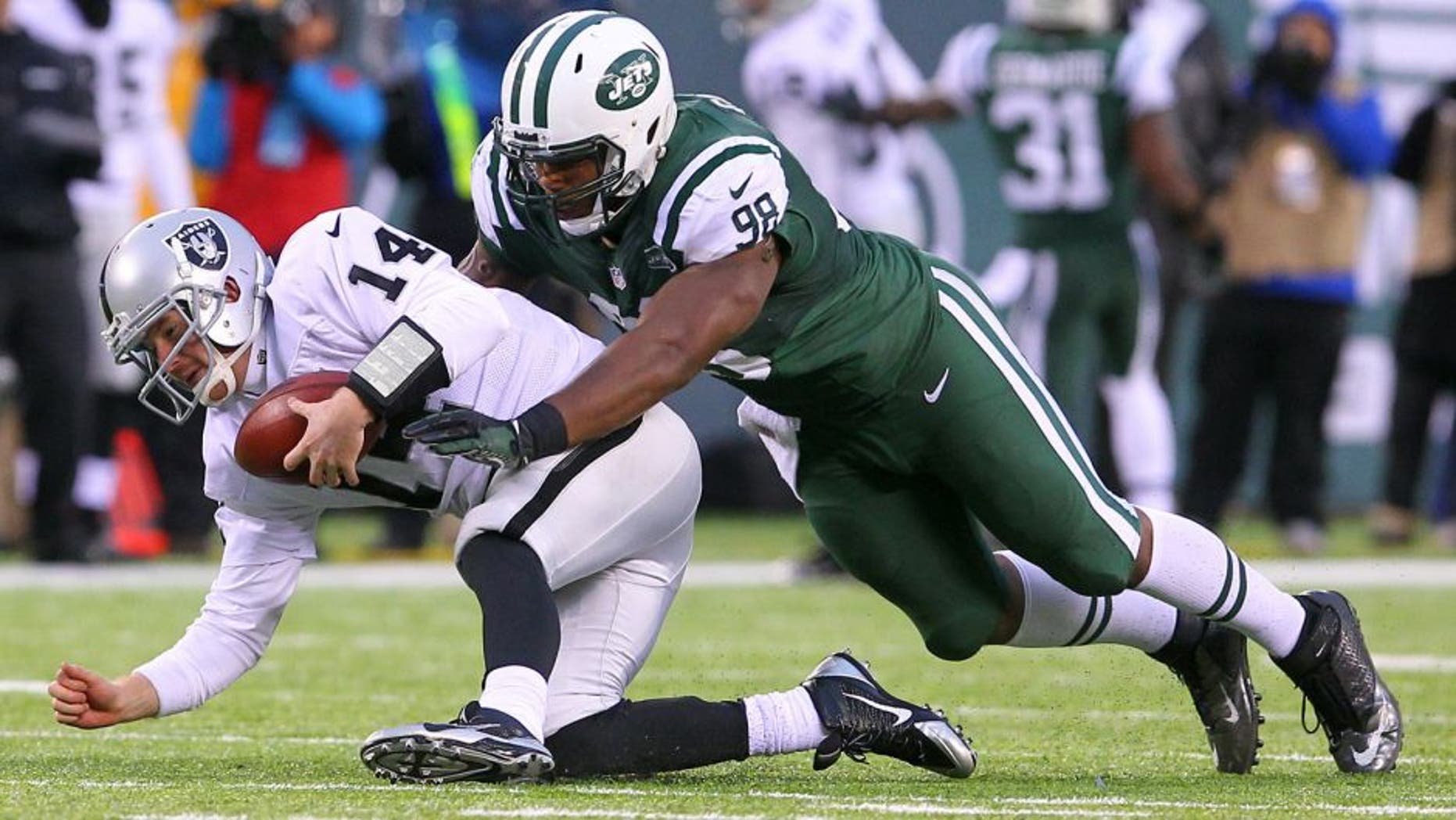 Dec 8, 2013; East Rutherford, NJ, USA; Oakland Raiders quarterback Matt McGloin (14) recovers his own fumble while being tackled by New York Jets defensive end Quinton Coples (98) during the second half at MetLife Stadium. The Jets defeated the Raiders 37-27. Mandatory Credit: Ed Mulholland-USA TODAY Sports