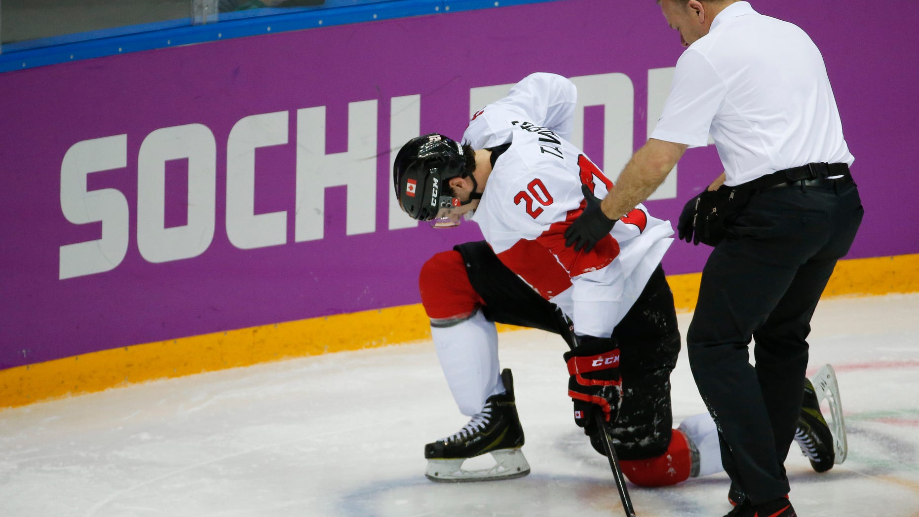 Canada forward John Tavares is helped up off the ice by a trainer during the second period of a men's quarterfinal ice hockey game against Latvia at the 2014 Winter Olympics, Wednesday, Feb. 19, 2014, in Sochi, Russia. Tavares is out for the rest of the Olympics with an unspecified leg injury. (AP Photo/Mark Humphrey)