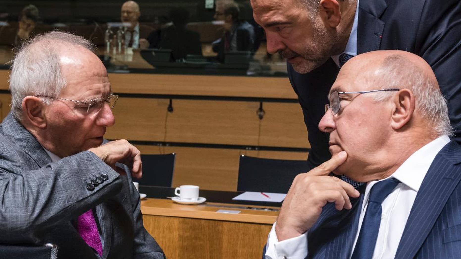 German Finance Minister Wolfgang Schauble, left, talks with Franch Finance Minister Michel Sapin, right, and European Commissioner for Economic Affairs, Taxation and Customs Pierre Moscovici during an EU finance ministers meeting at the EU Council in Luxembourg Tuesday, Oct. 11, 2016. (AP Photo/Geert Vanden Wijngaert)