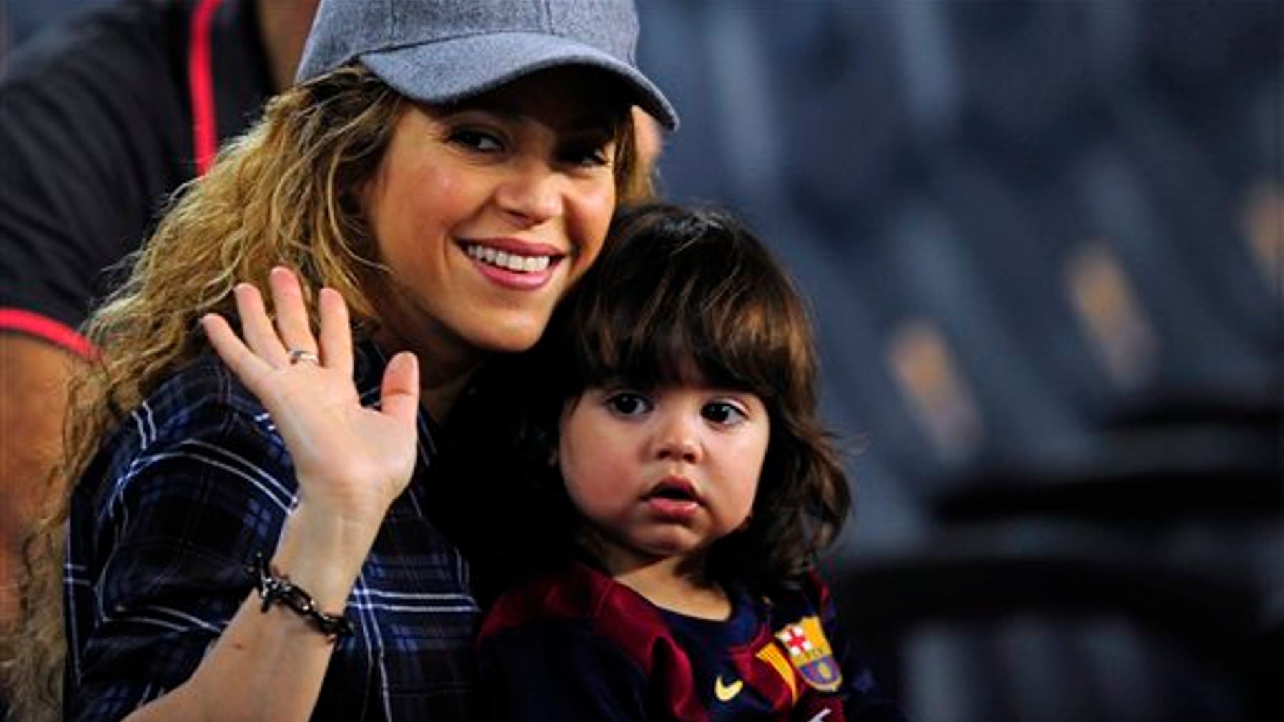 Colombian singer Shakira, left, waves with his son Milan prior of a Spanish La Liga soccer match between FC Barcelona and Eibar at the Camp Nou stadium against Eibar in Barcelona, Spain, Saturday, Oct. 18, 2014. (AP Photo/Manu Fernandez)