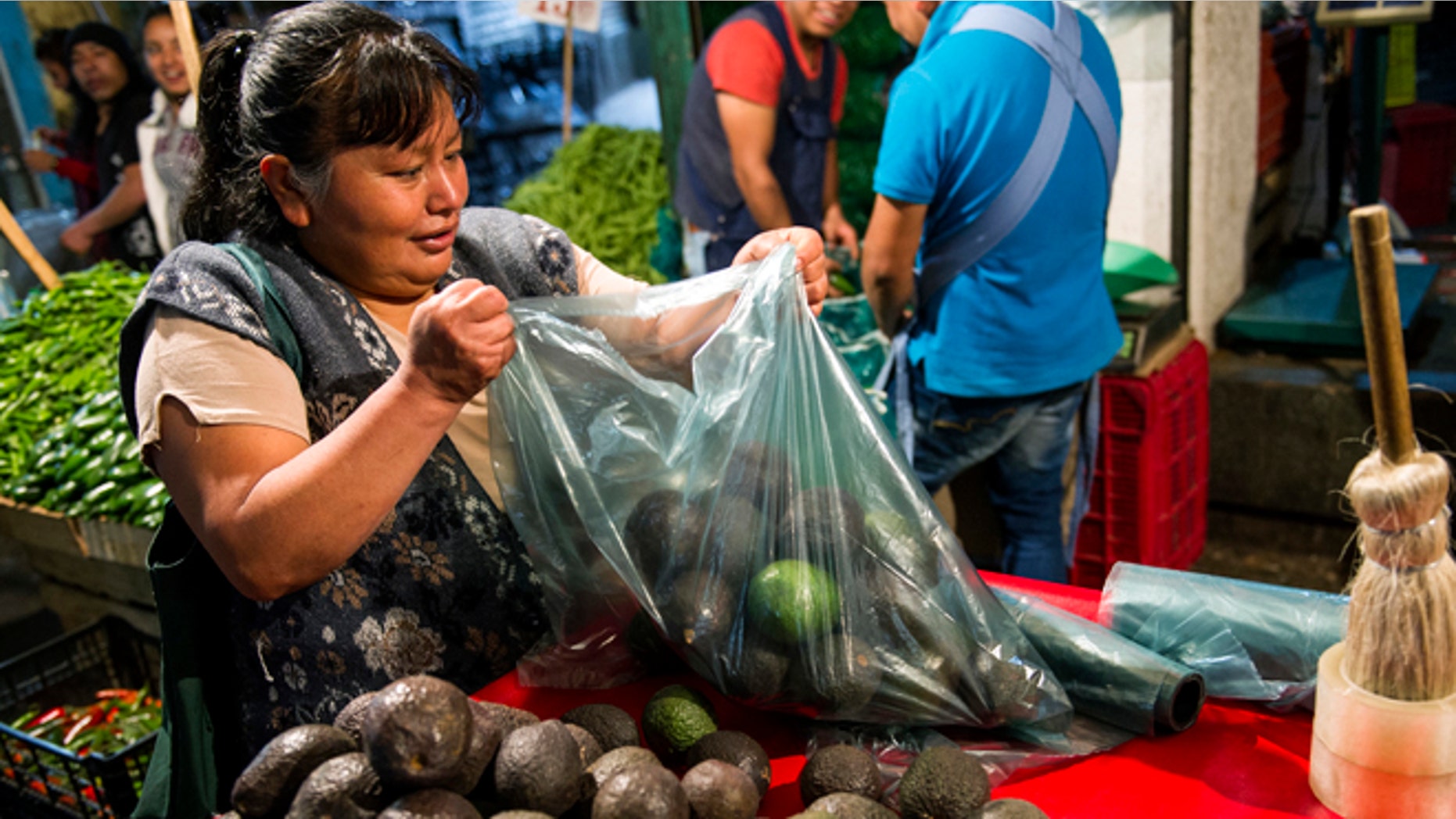 A woman prepares a bag of avocados in Mexico City, Tuesday, Aug. 9, 2016.