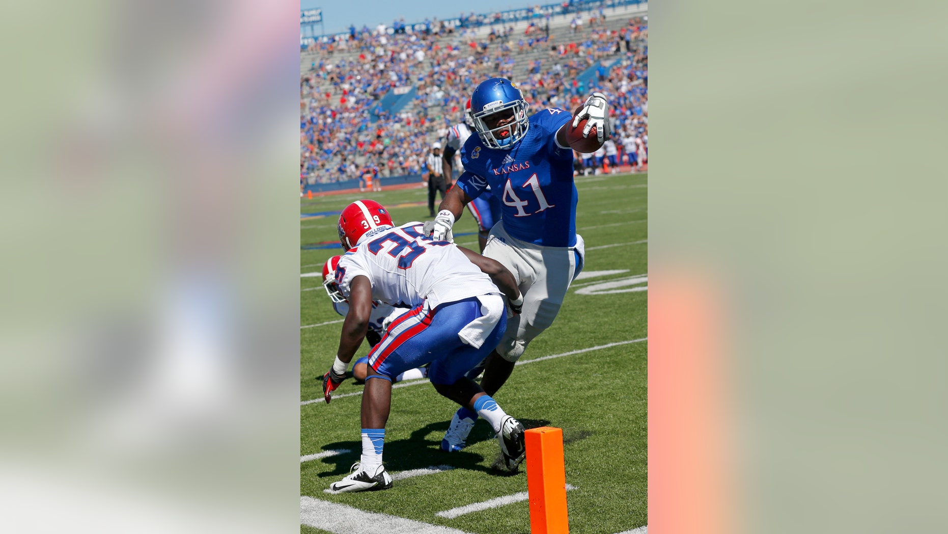 FILE - In this Sept. 21, 2013, file photo, Kansas tight end Jimmay Mundine (41) slips past Louisiana Tech defensive back Xavier Woods (39) for a touchdown during the second half of an NCAA college football game in Lawrence, Kan. Just about the only bright spot in the Kansas pass attack this season has been the guy who was perhaps the least expected to make a contribution: tight end Jimmay Mundine. He's also the only guy catching touchdown passes. (AP Photo/Orlin Wagner, File)