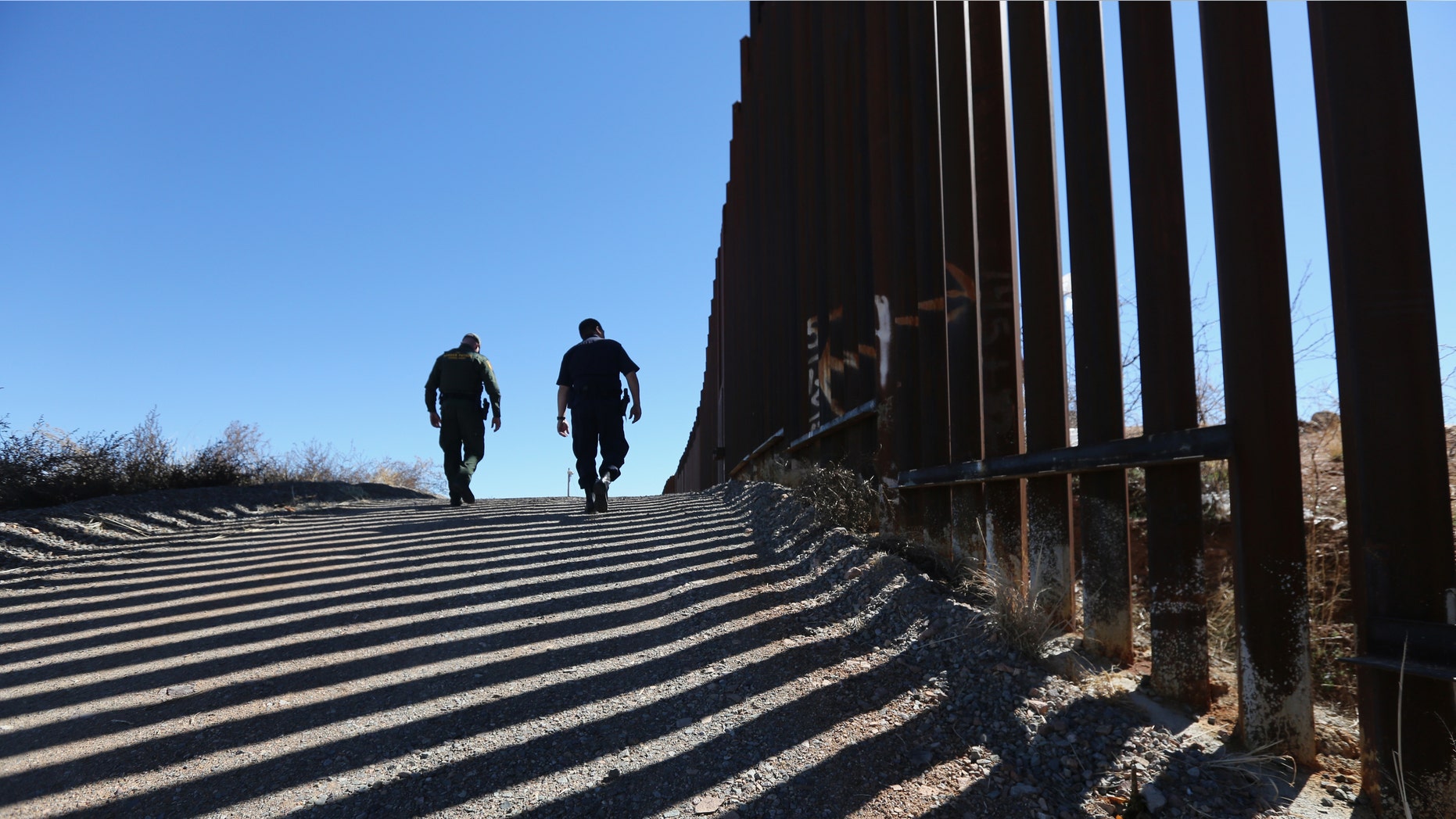 NOGALES, AZ - FEBRUARY 26: U.S. Customs and Border Protection personnel walk along a section of the recently-constructed fence at the U.S.-Mexico border on February 26, 2013 in Nogales, Arizona. The newest generation of fencing allows Border Patrol agents to see through the fence and is harder to scale from the Mexican side. (Photo by John Moore/Getty Images)