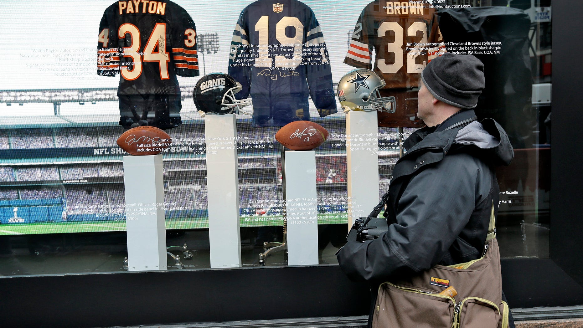 Football fan Brian Jackson, of Newark, N.J. stops to look at autographed memorabilia of NFL Hall of Fame players, Walter Payton, Johnny Unitas, and Jim Brown at a store along Super Bowl Boulevard Friday, Jan. 31, 2014, in New York. The Denver Broncos take on the Seattle Seahawks in Super Bowl XLVIII Sunday at Metlife Stadium in East Rutherford, N.J. (AP Photo/Chris O'Meara)