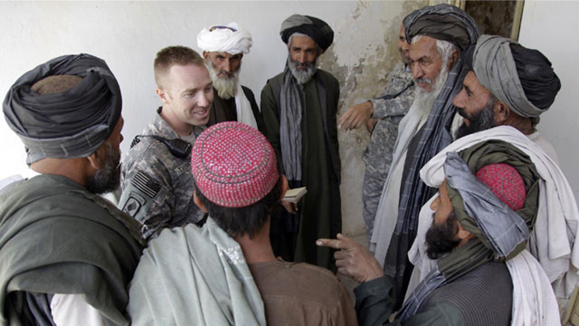 In this Wednesday, April 28, 2010 photo, U.S. Army Capt. Casey Thoreen, second from left, of Seattle, Wash., Bravo Company, 2nd Battalion, 1st Infantry Regiment, 5th Stryker Brigade, talks with village leaders before the start of a shura , in the Maiwand district of Afghanistan's Kandahar province. To the locals, he is the "King of Maiwand" district testimony to the fact that without the resources the young captain and others like him provide, local government in much of insurgency-ravaged southern Afghanistan could not function at all.