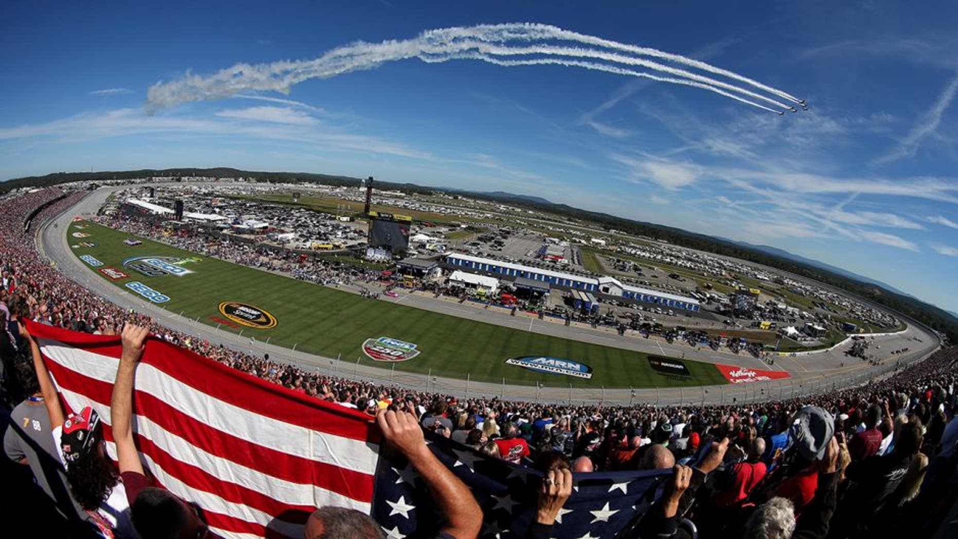TALLADEGA, AL - OCTOBER 19: Fans hold up an American flag during the flyover peior to the NASCAR Sprint Cup Series GEICO 500 at Talladega Superspeedway on October 19, 2014 in Talladega, Alabama. (Photo by Todd Warshaw/Getty Images)