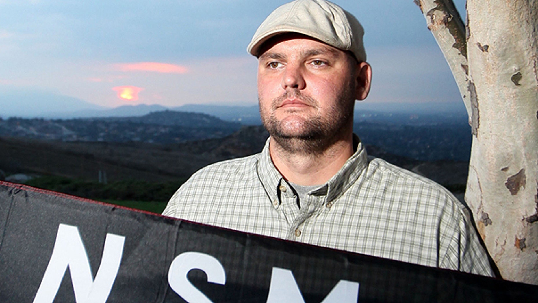 In this file photo taken Friday, Oct. 22, 2010, Jeff Hall holds a Neo Nazi flag while standing at Sycamore Highlands Park near his home in Riverside, Calif.