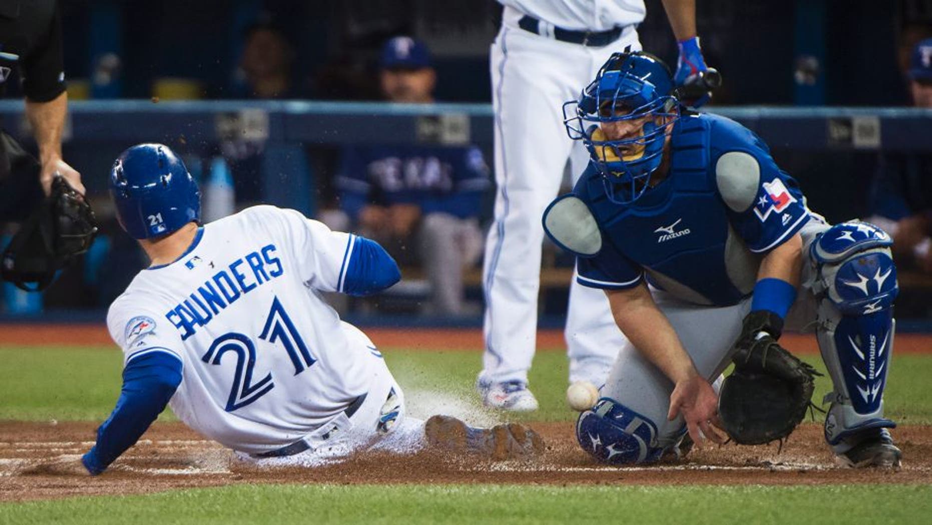 Toronto Blue Jays left fielder Michael Saunders (21) sides safe at home plate past Texas Rangers catcher Bobby Wilson, right, during the first inning of a baseball game, Wednesday, May 4, 2016, 2016 in Toronto. (Nathan Denette/The Canadian Press via AP) MANDATORY CREDIT